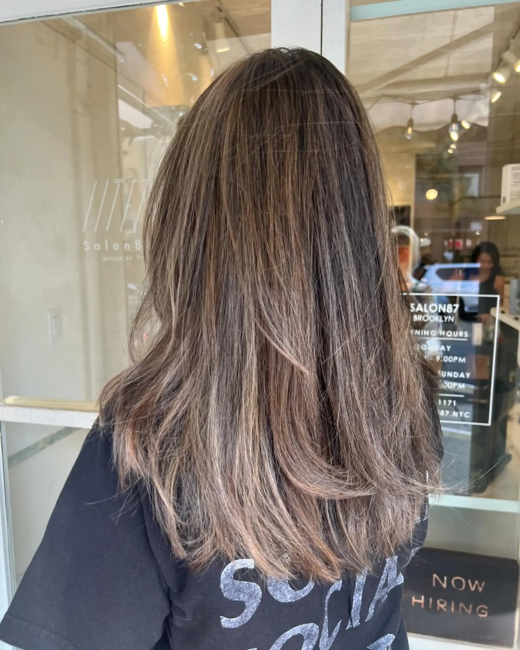 Long, wavy hair with a layered cut, featuring brown base and ashy blonde highlights for a natural, sun-kissed effect.