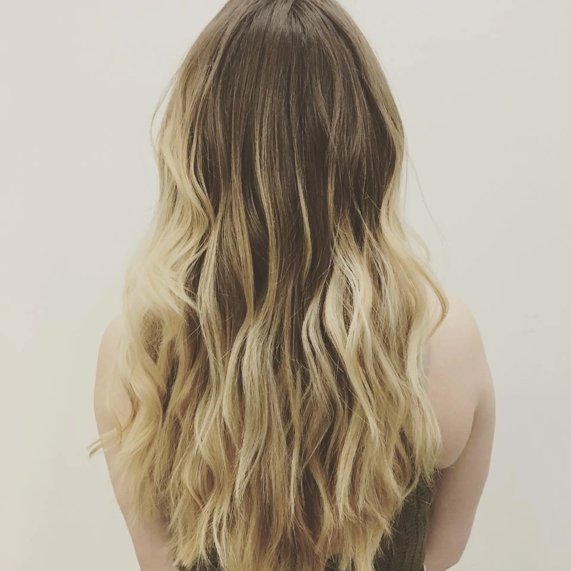 Long brown hair transitioned into bright blonde balayage, styled with loose textured waves. 1