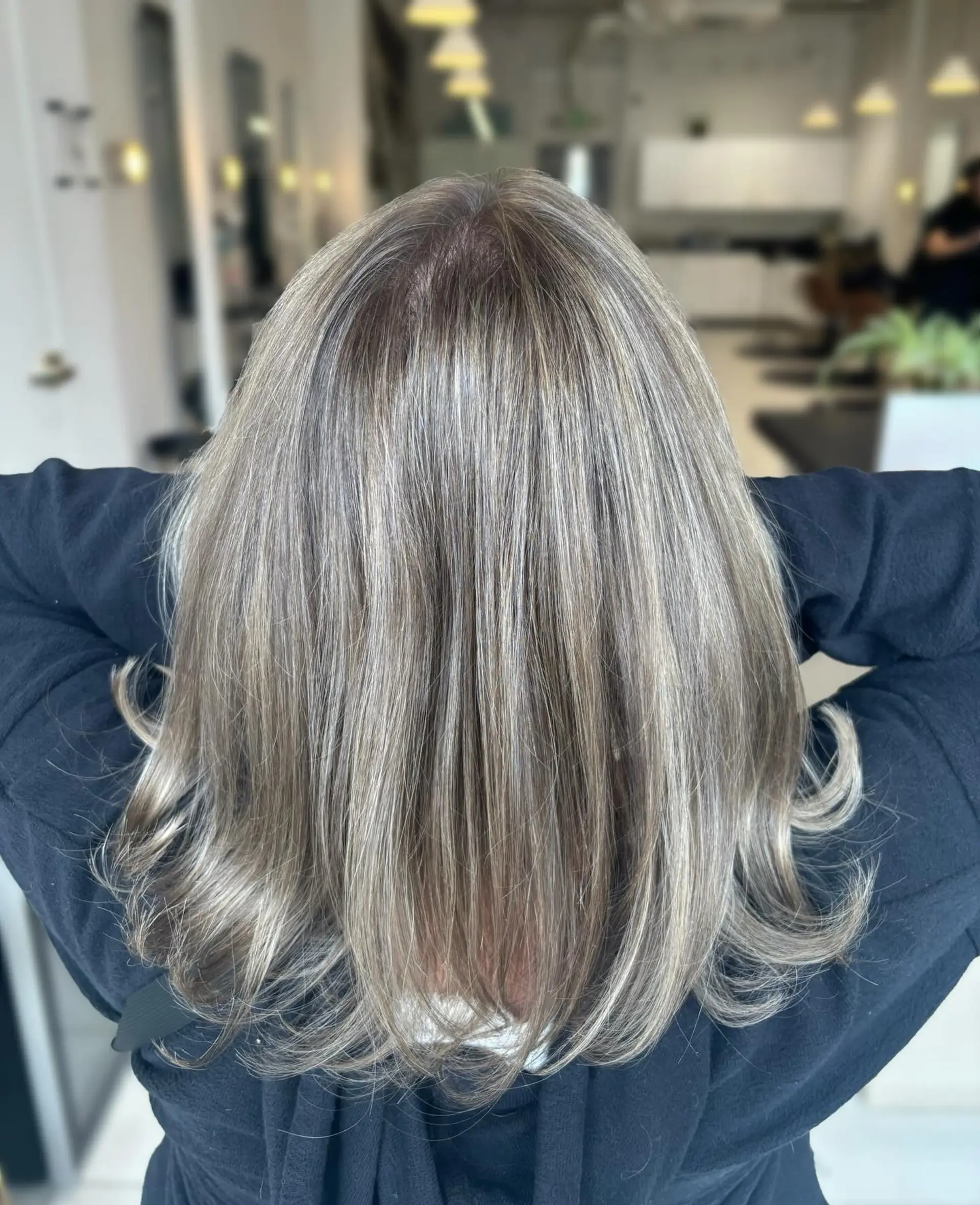 Medium-length layered haircut with a seamless blend of cool-toned ash blonde highlights and softly flipped ends. 1