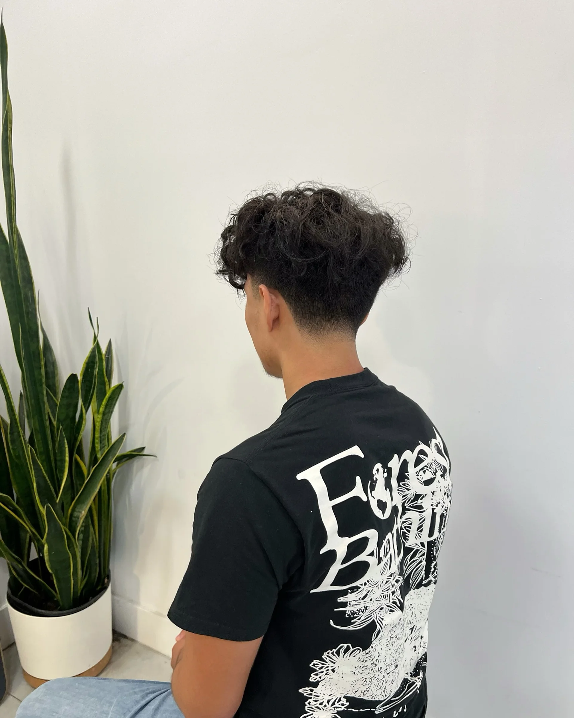 Man with a textured curly taper fade, a top men's curly hair trend for 2025 in NYC, showcasing sharp lines and natural texture. - Preview 1