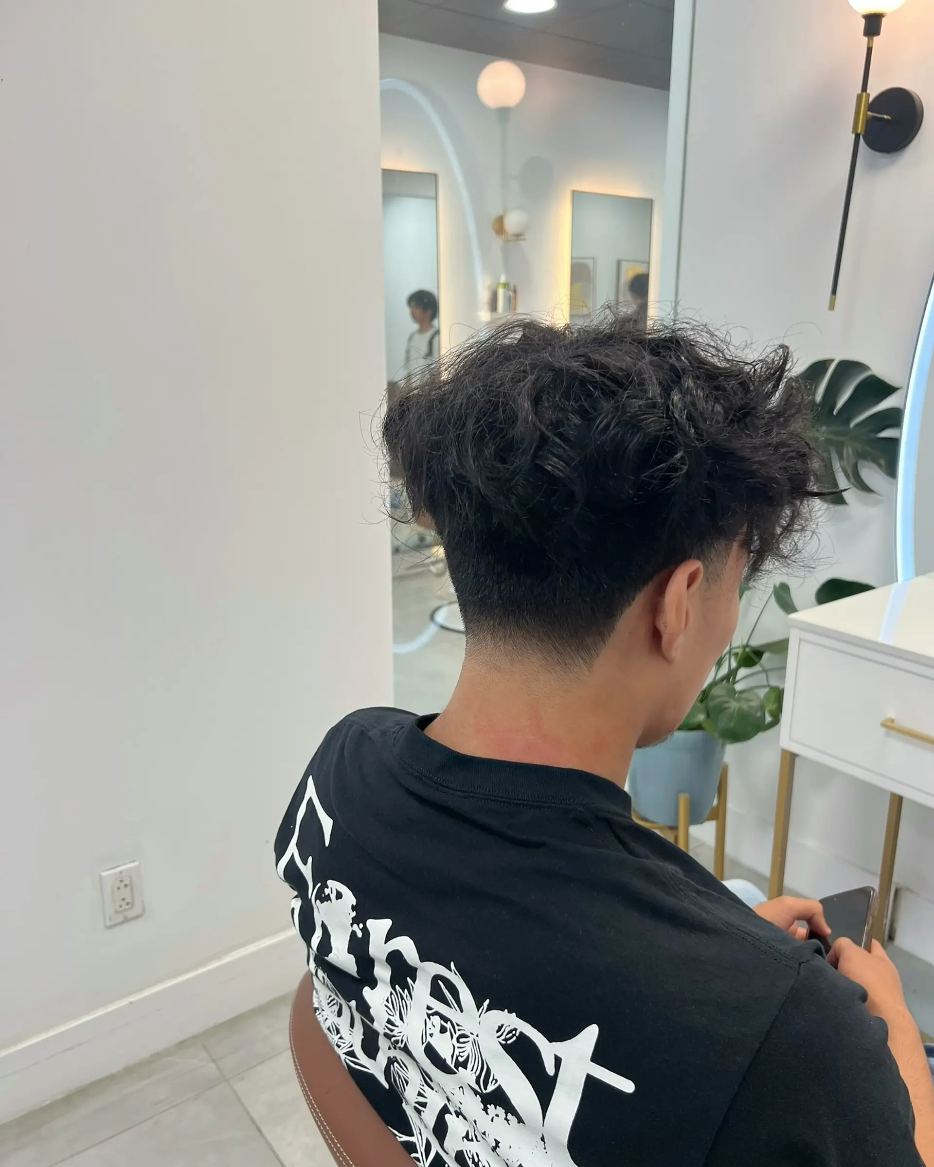 This hairstyle features medium length curly hair with a low taper fade. 2