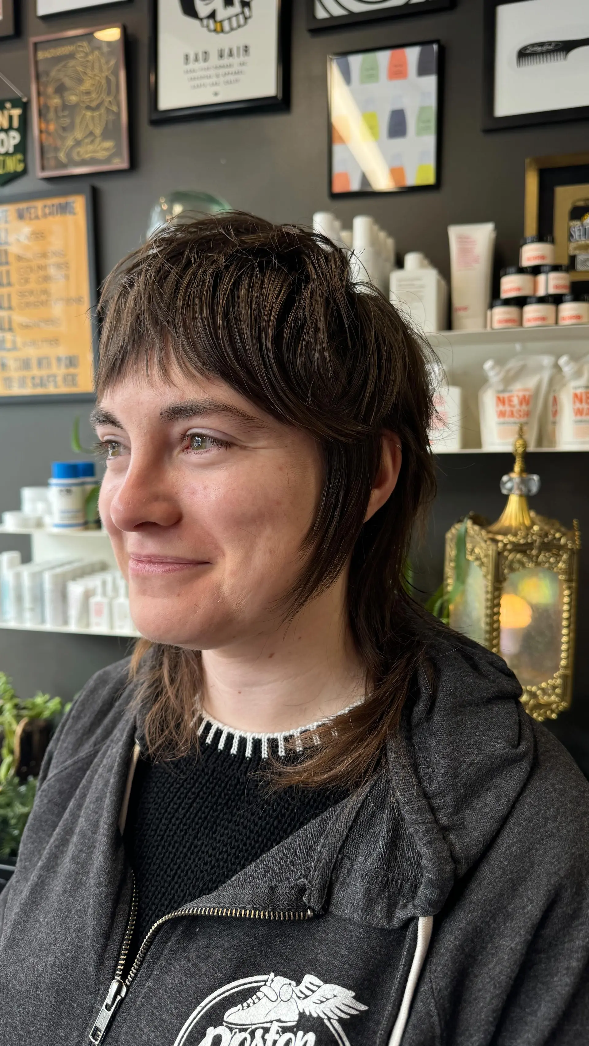 A modern textured shag mullet featuring short choppy micro bangs, tapered face-framing sideburn strands, and a longer textured tail at the nape. 1