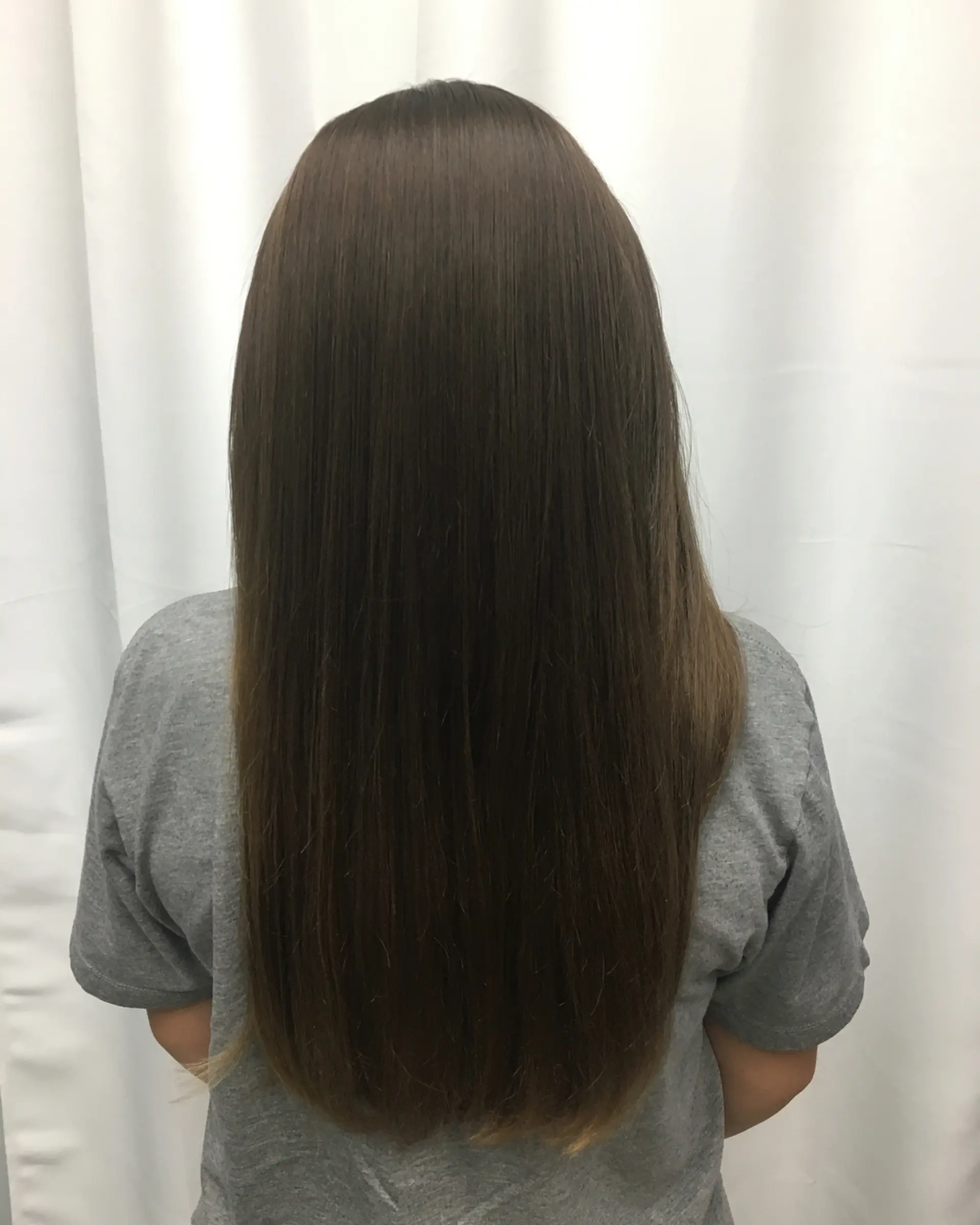 Long, sleek brunette hair styled pin-straight with a smooth, glossy finish. 1