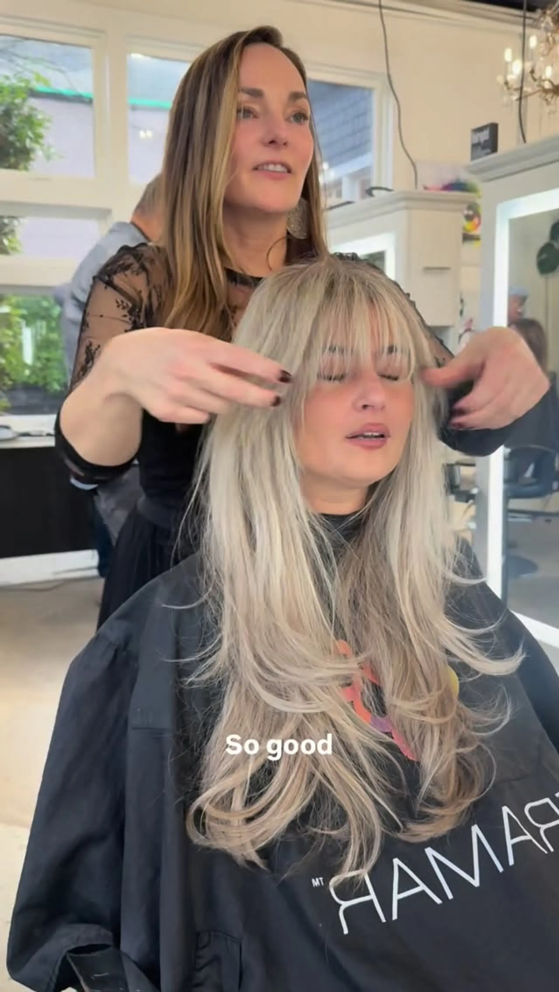 Long ash blonde hair styled with face-framing layers and soft, eyelash-grazing wispy bangs. 1