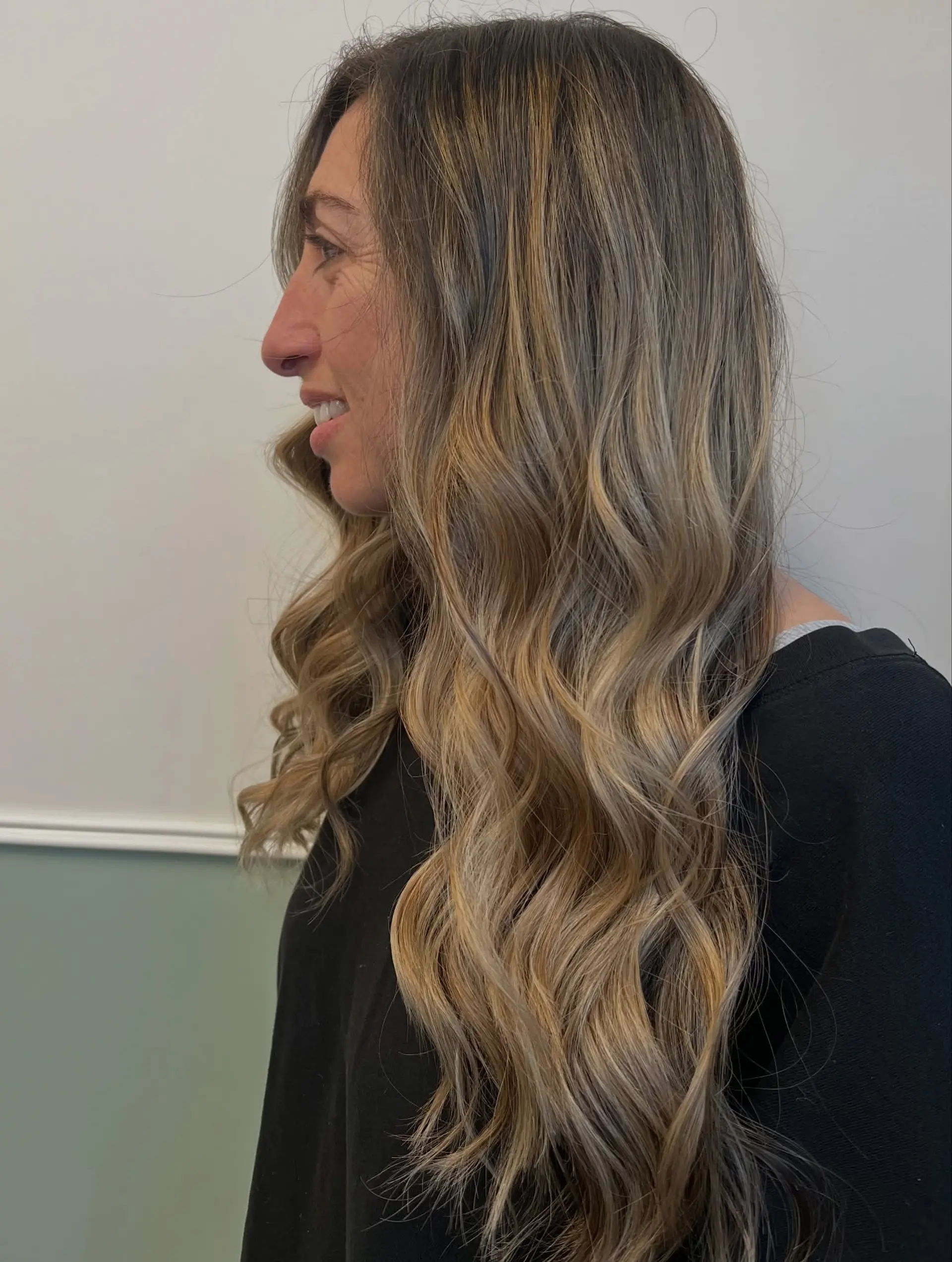 Long hair featuring a dimensional blonde balayage styled in soft, loose waves. 1