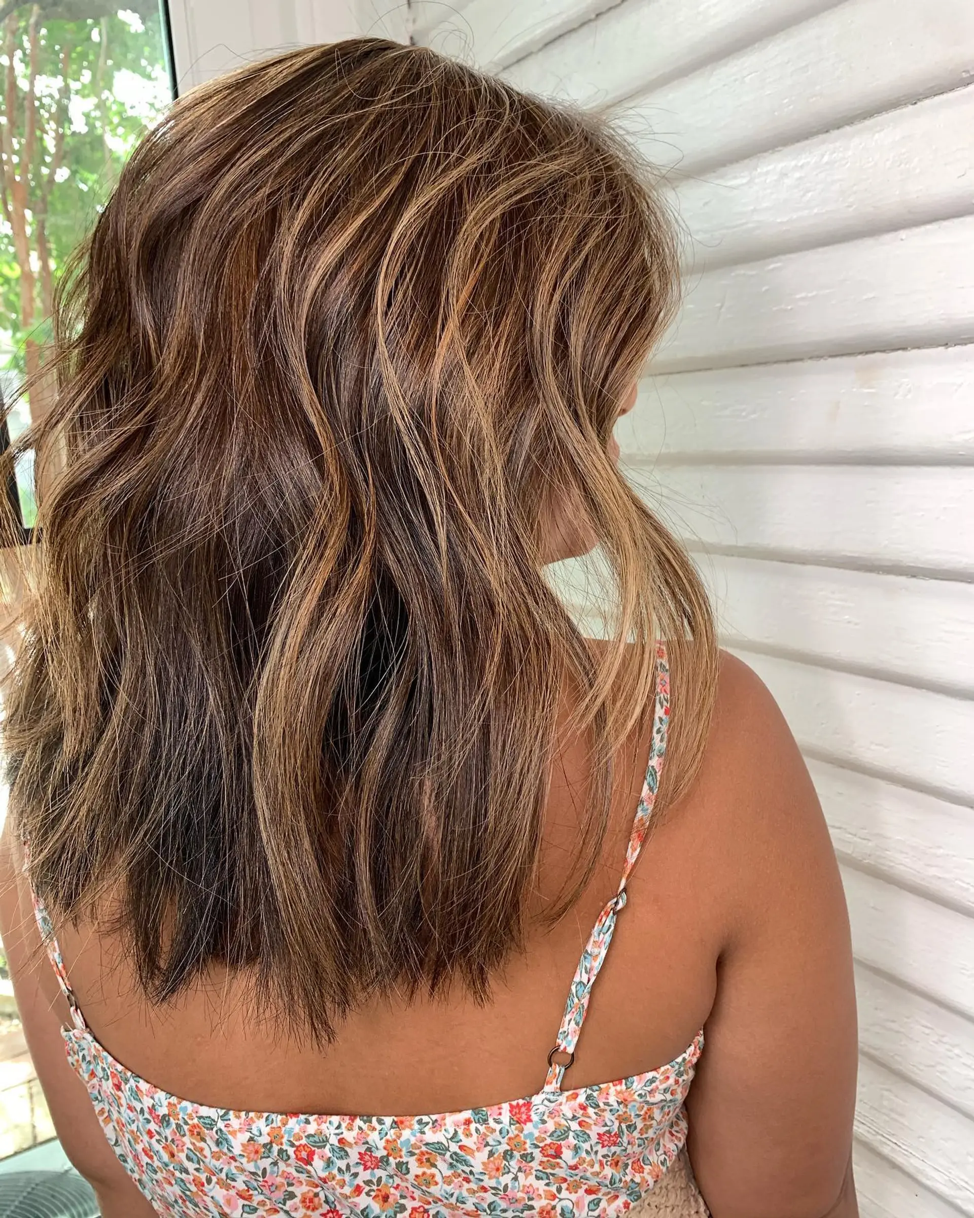 A medium-length textured lob styled in effortless beach waves with warm caramel highlights throughout. 1