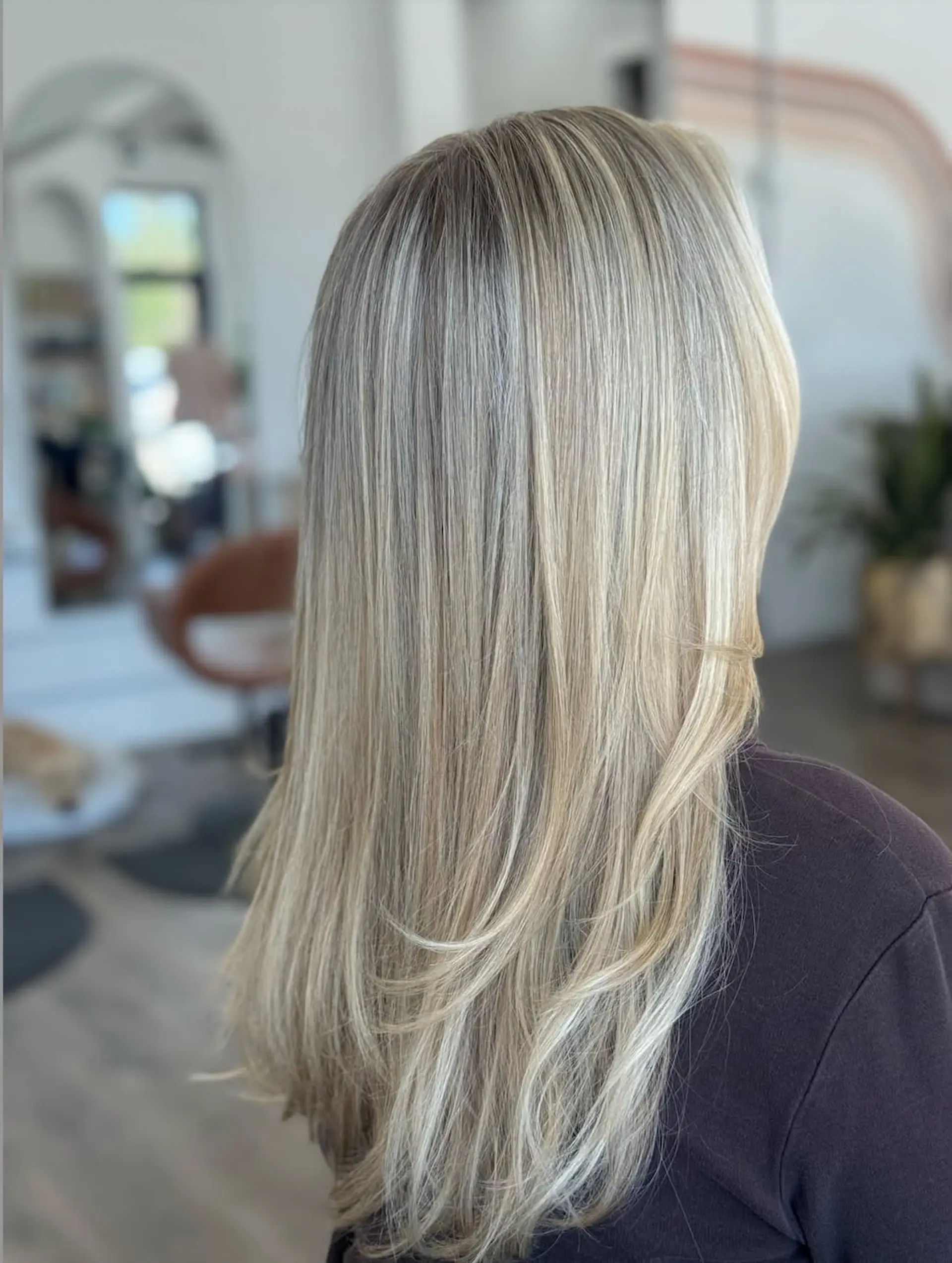 Long ash blonde hair with soft multi-dimensional highlights, styled straight with layered curved ends. 1