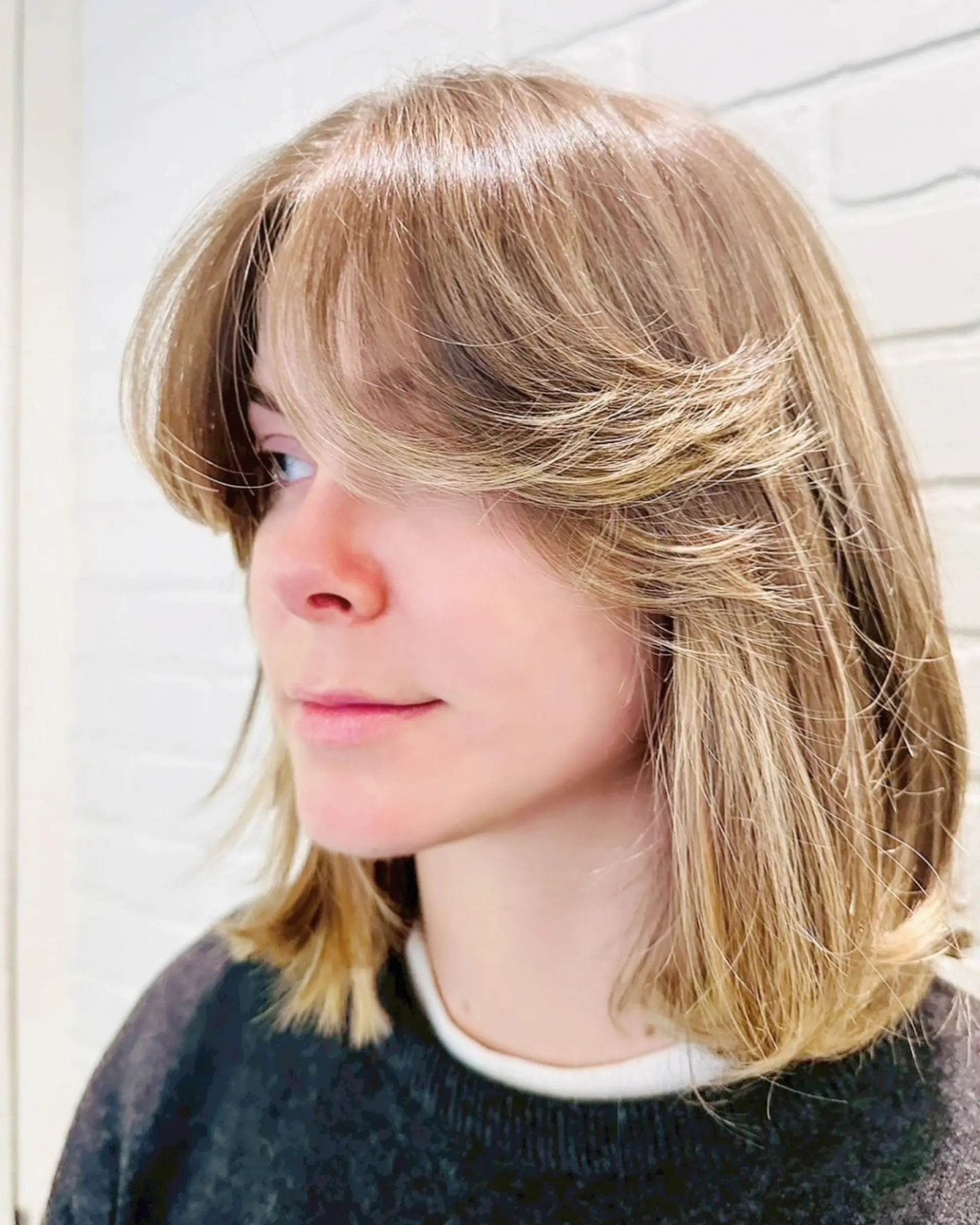 A medium-length bob featuring feathered, face-framing curtain bangs that flick outward softly. 1