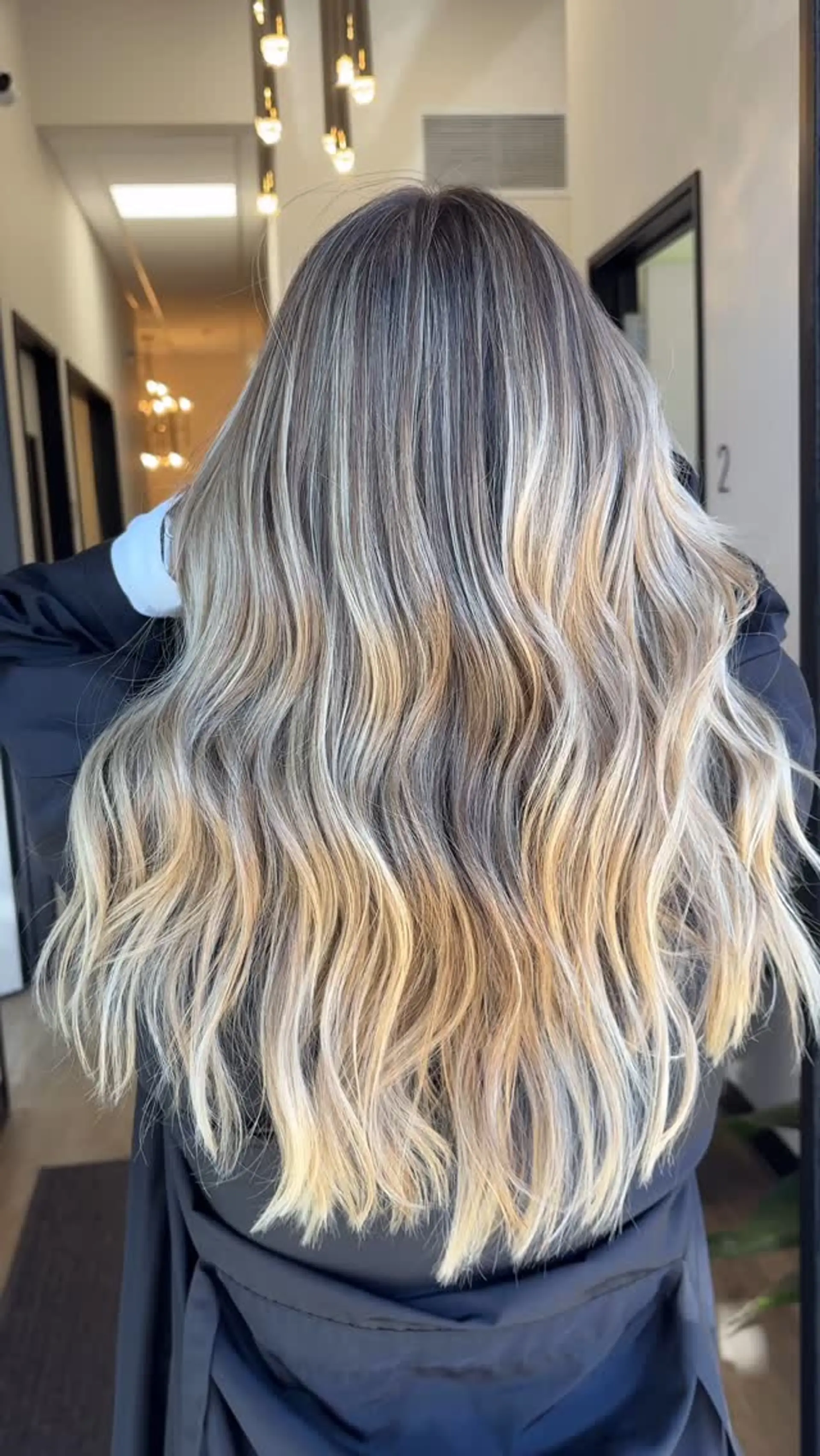 Long dimensional blonde hair with soft, loose waves and seamless root blending. 1