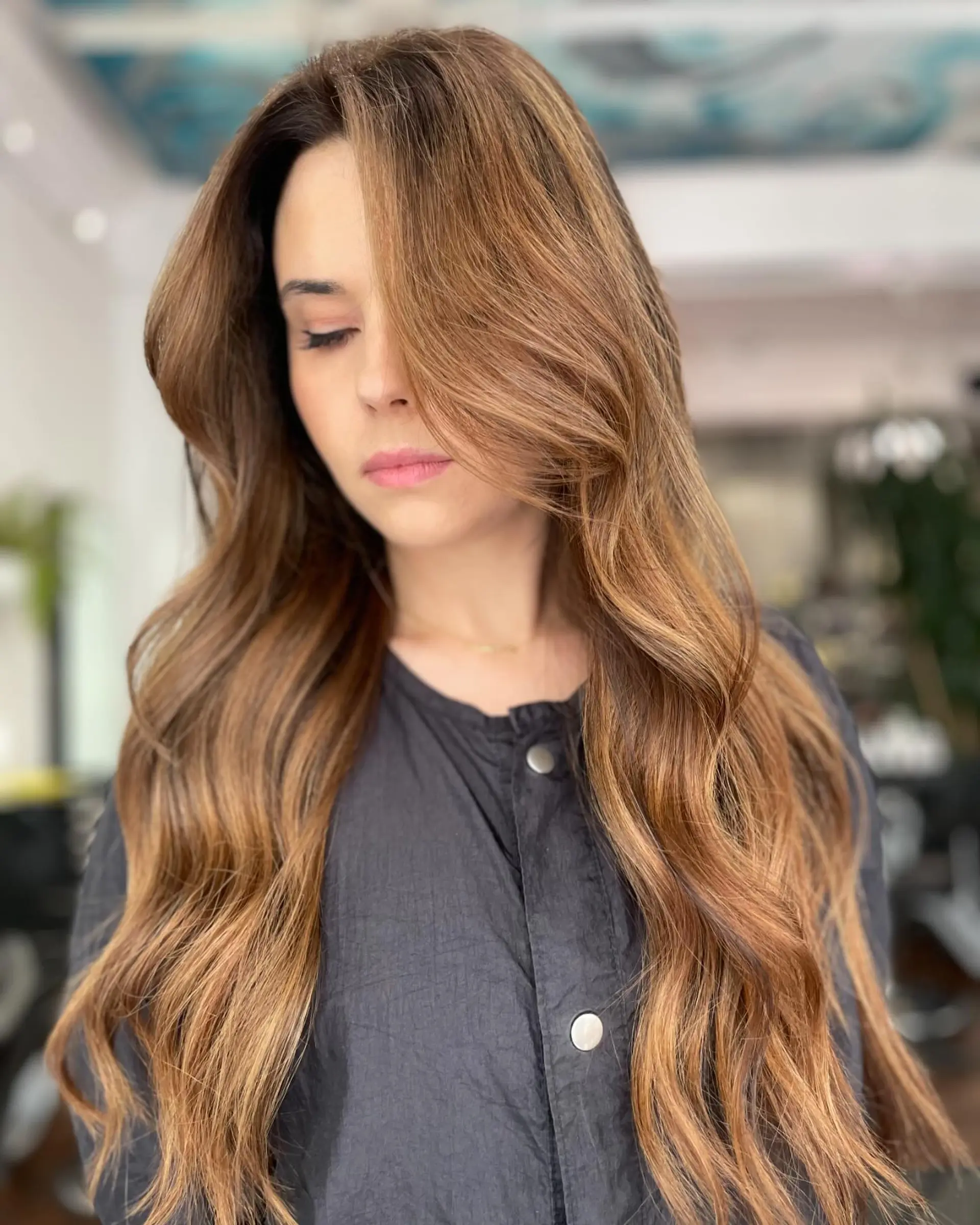 Long dimensional bronde hair with warm caramel balayage styled in soft, sweeping waves. 1