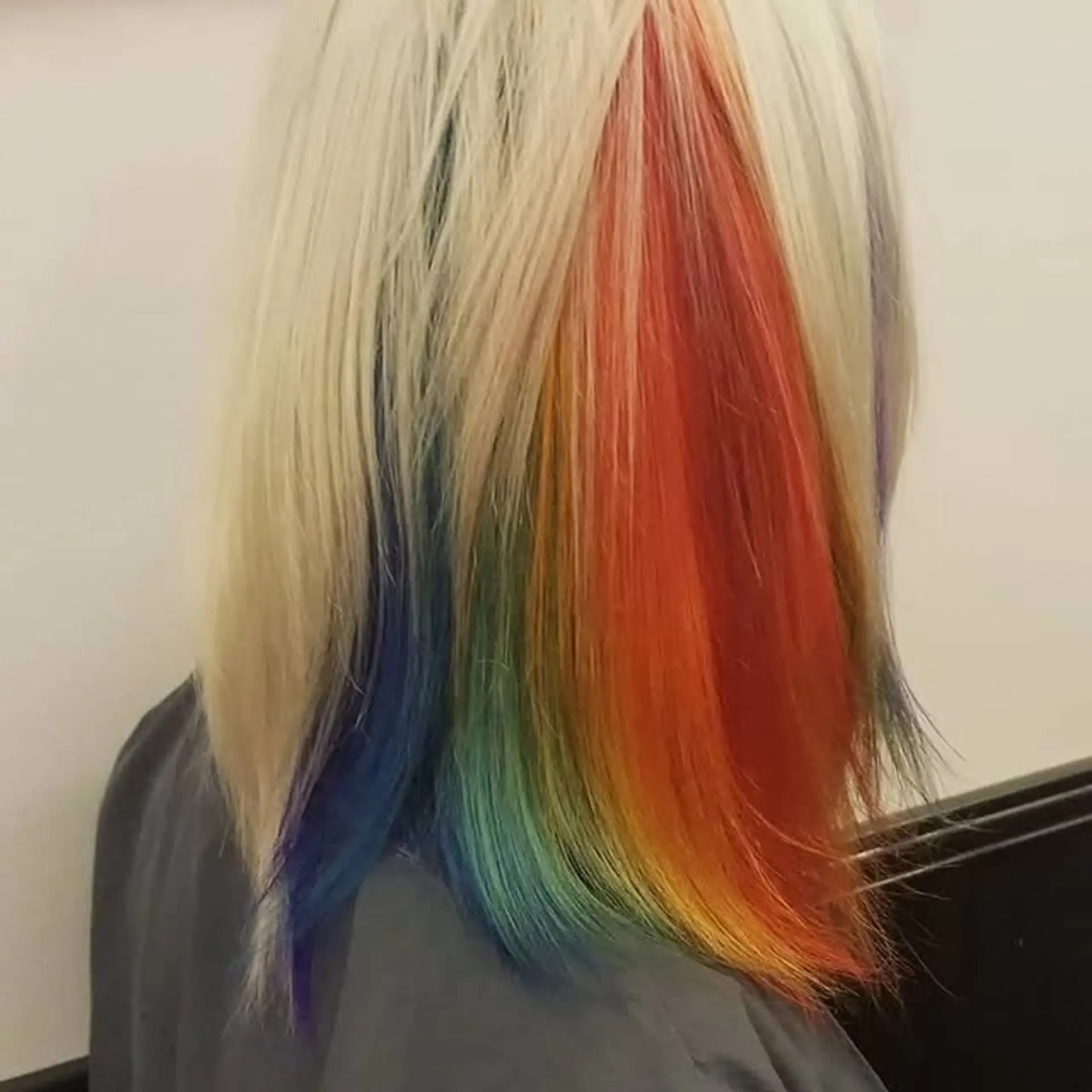A sleek, medium-length straight cut with a dominant platinum blonde top layer, subtly concealing vibrant rainbow stripes underneath for a fun peekaboo effect. 1