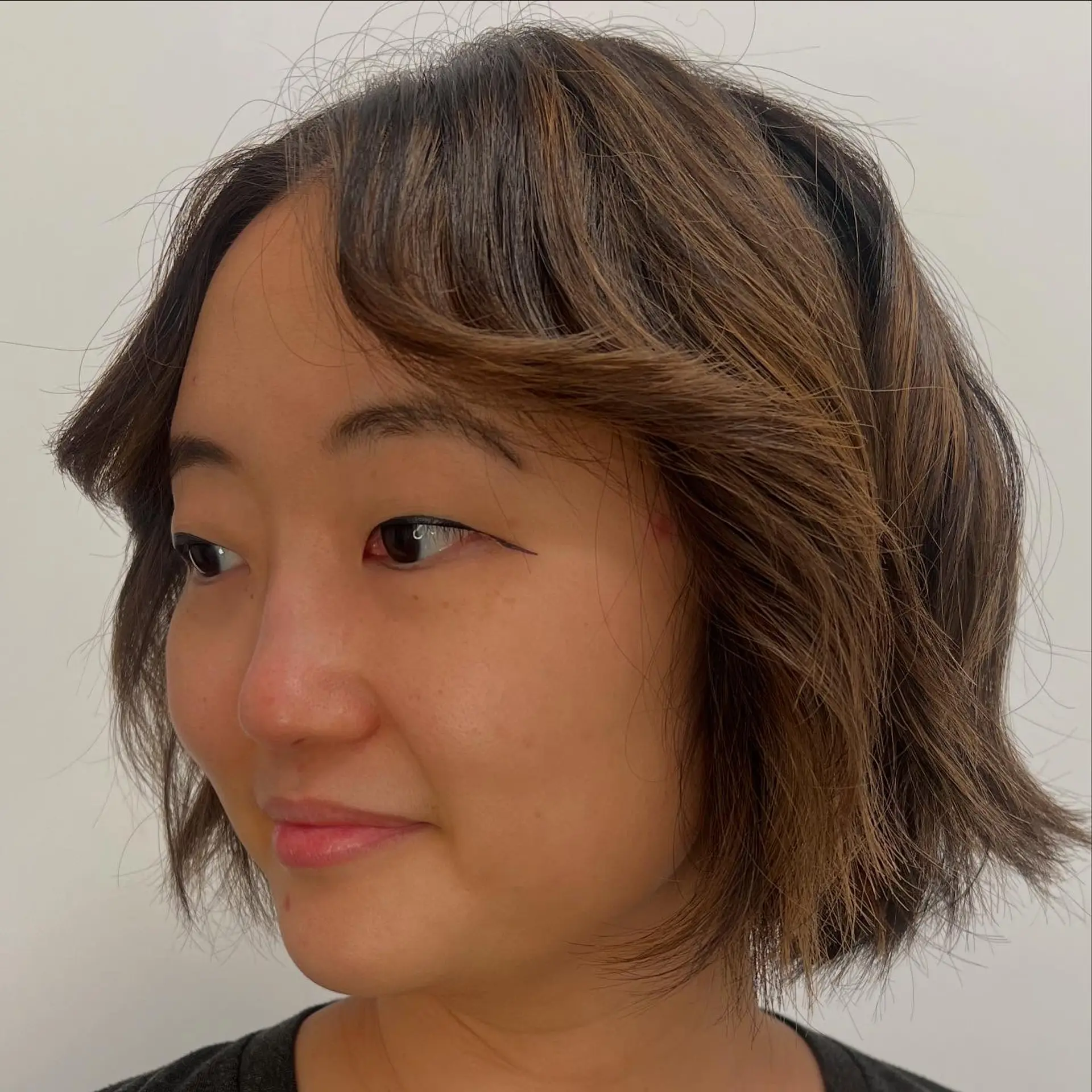 A textured chin-length short bob styled with soft waves and outward-curving curtain bangs. 1