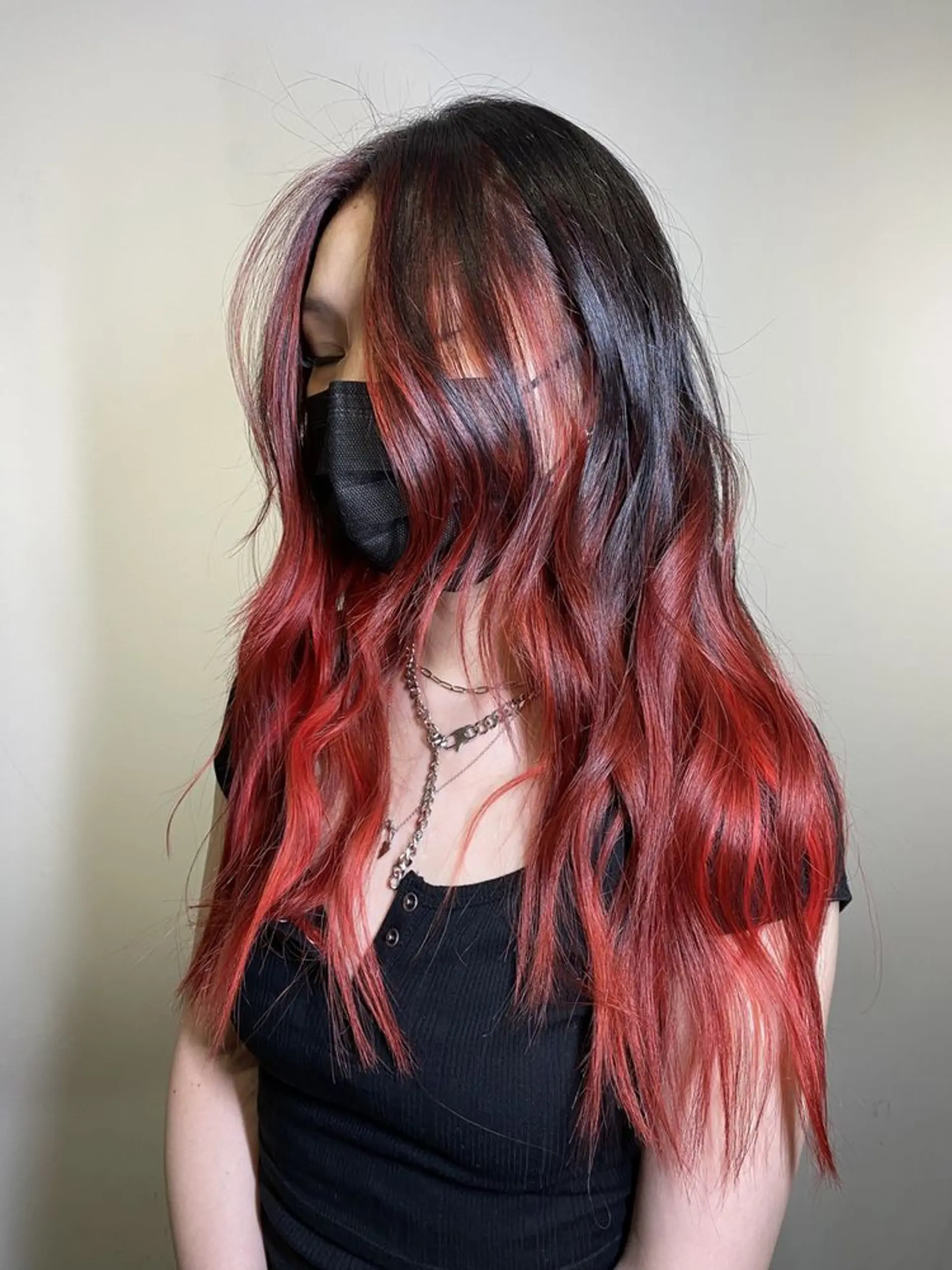 Long, wavy tresses with a black to red ombre effect, featuring subtle layers and soft waves, creating volume and a face-framing, bold look. 1