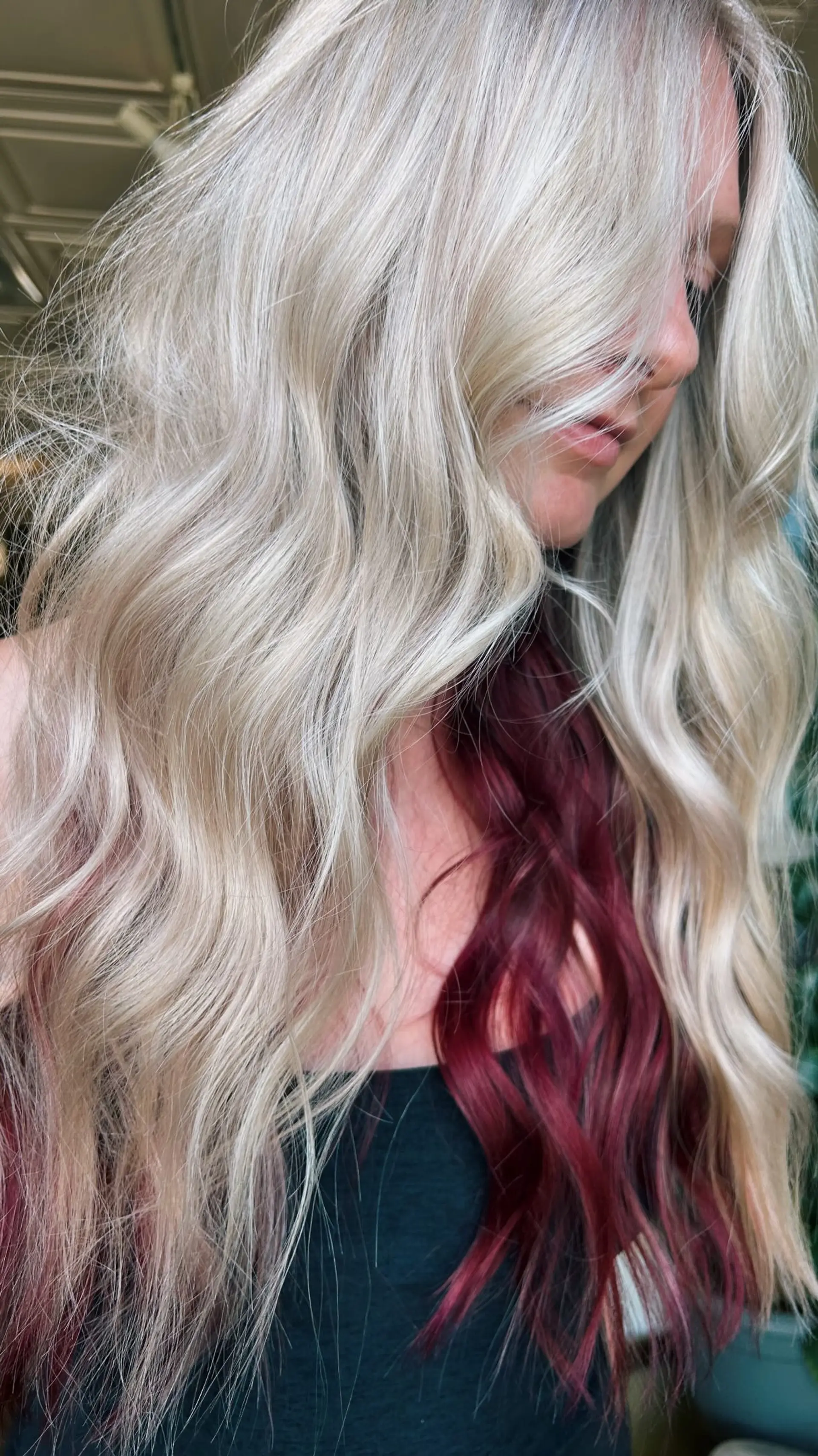 Long wavy platinum blonde hair featuring a bold, contrasting magenta-red peekaboo underlayer. 1