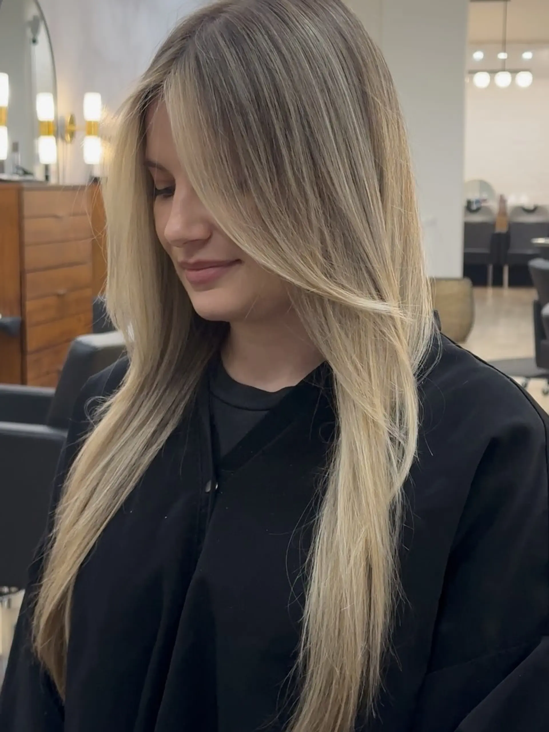 Long, smooth lived-in blonde hair styled straight with soft, face-framing curtain layers and a seamless, dimensional root. 1