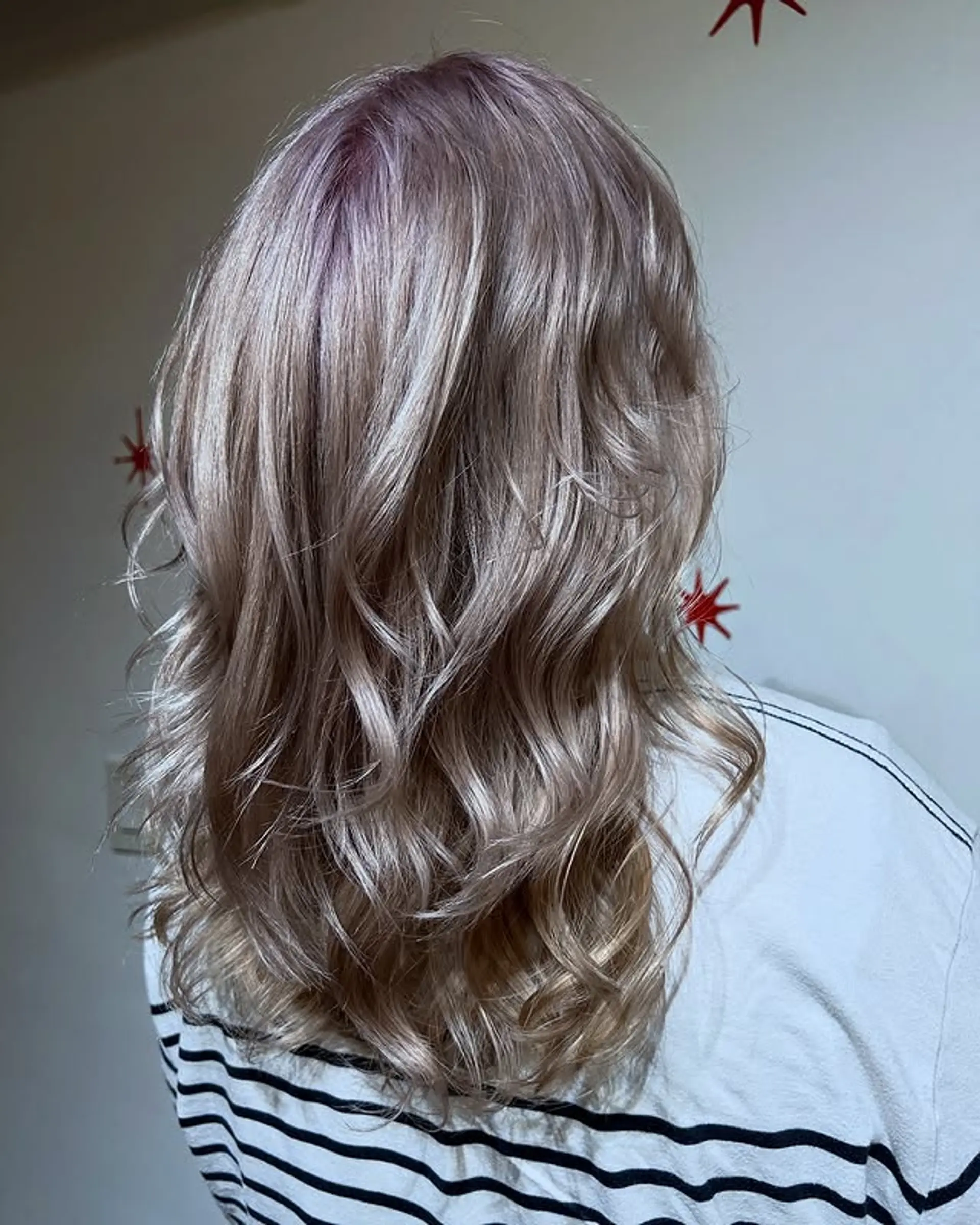 Medium-length wavy hairstyle with icy blonde balayage and dark purple shadow root. 1