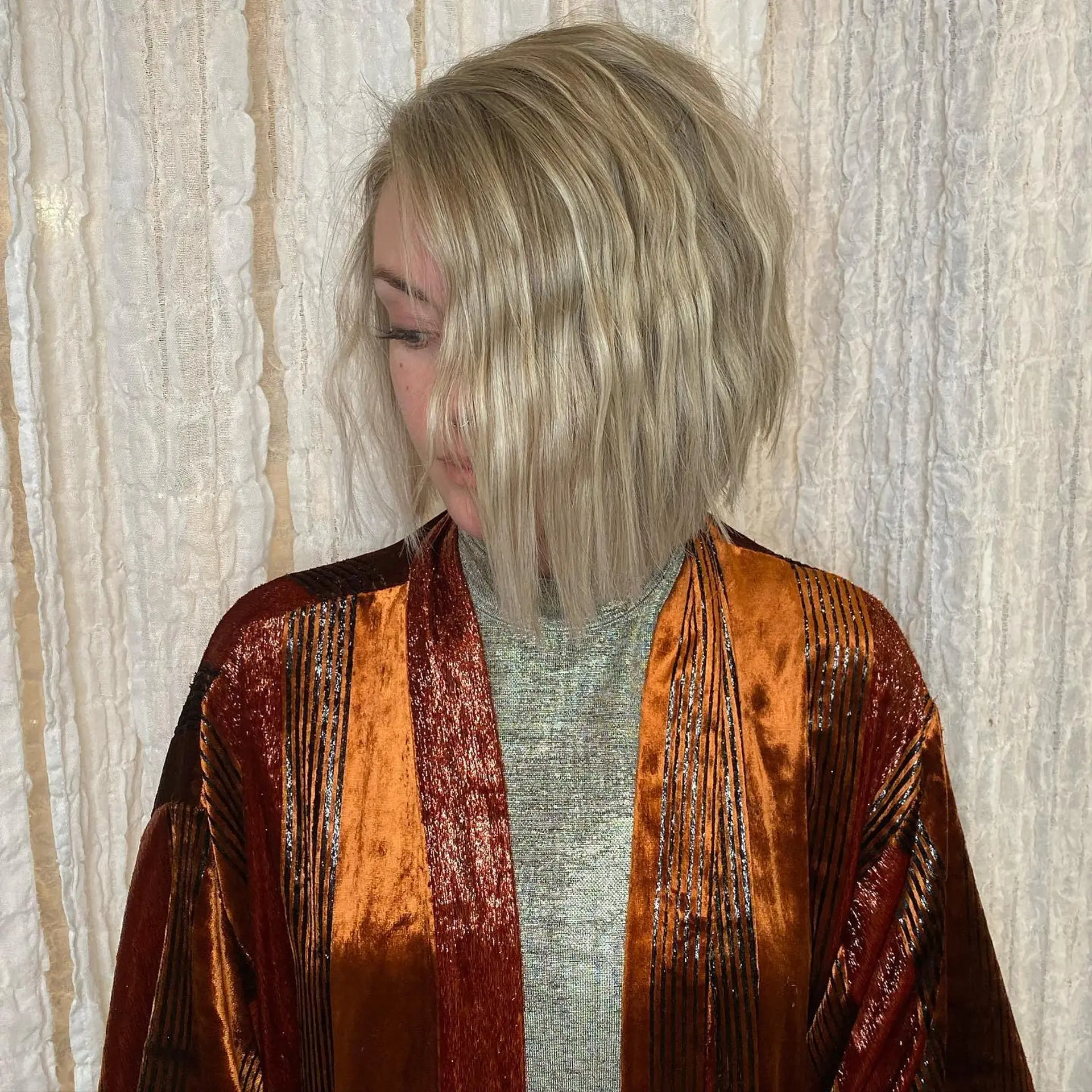 A cool-toned icy blonde bob styled with crimped, undone texture and an angled silhouette falling just past the jawline. 1