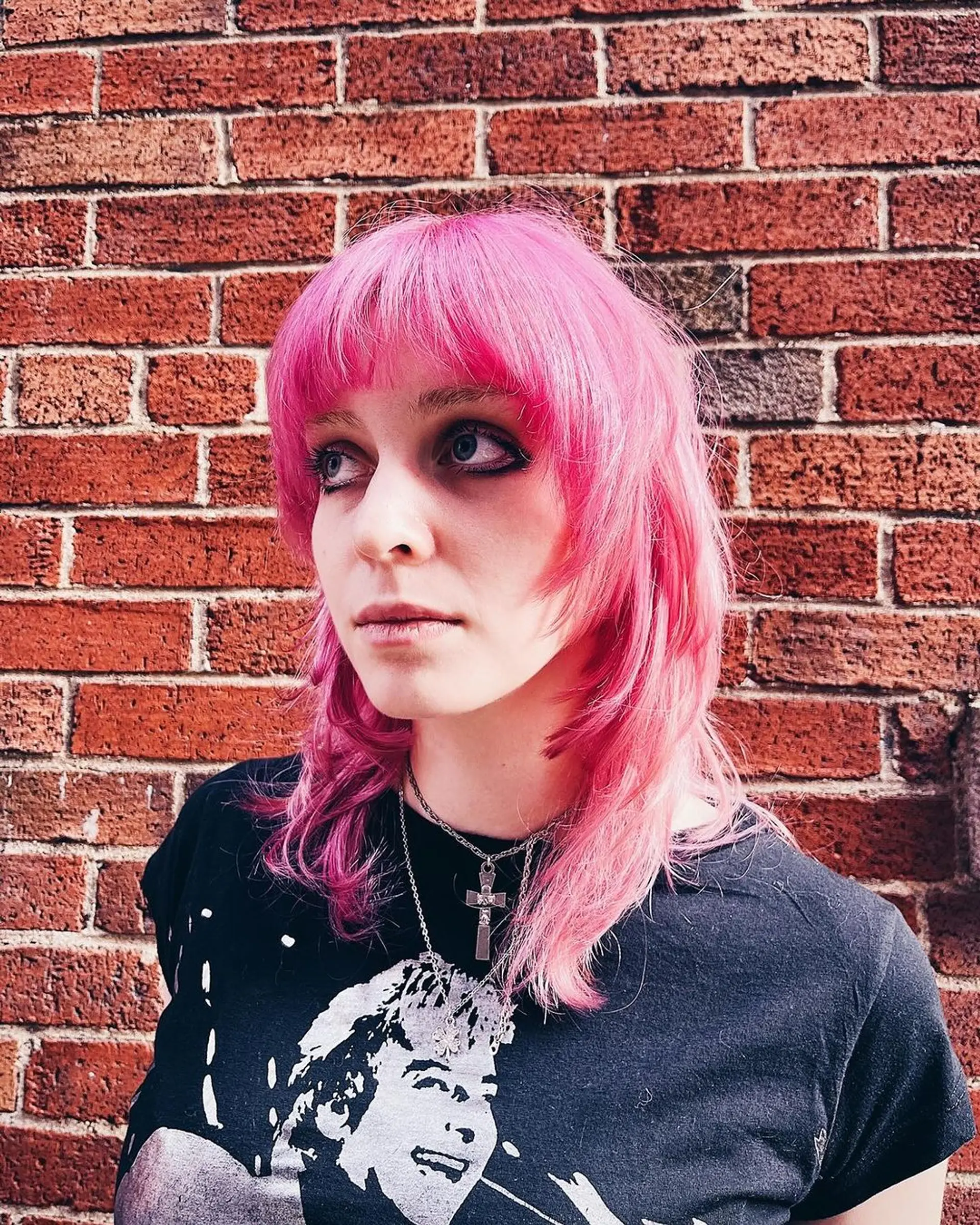 A vibrant pink medium-length mullet featuring layers, wavy texture, and a soft fringe of bangs covering the forehead, creating a look full of movement and definition by Lynn. 1