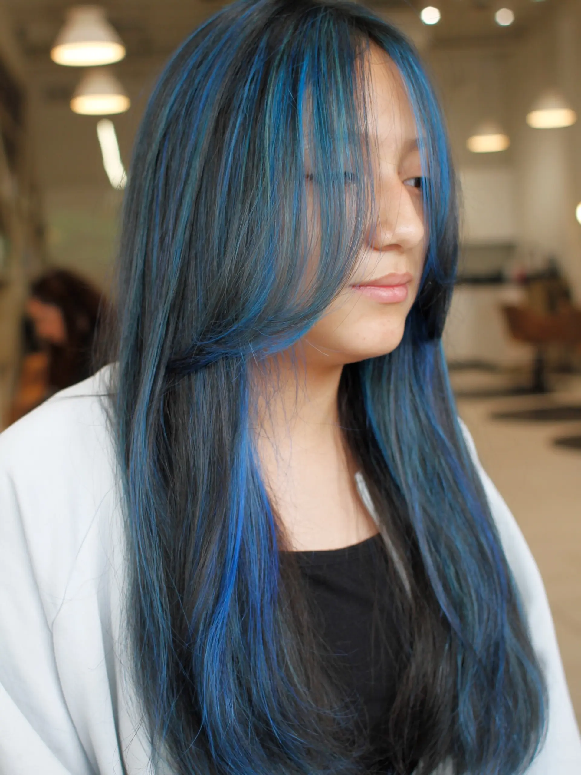 Long straight dark hair accented with electric blue face-framing highlights and subtle layers. 1