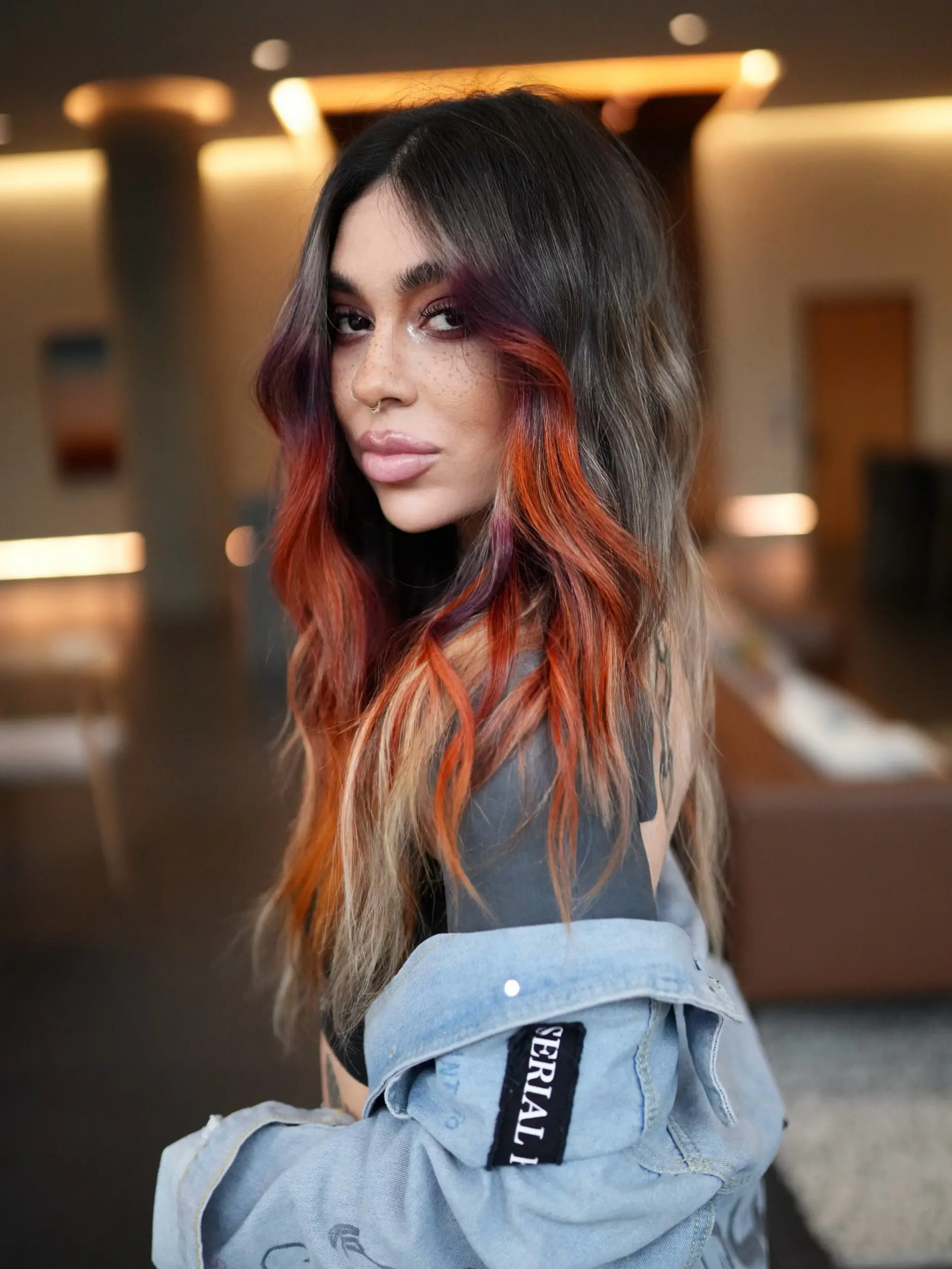 Long wavy brunette hair highlighted with a vibrant sunset-toned face frame featuring orchid, coral, and fiery orange hues. 1