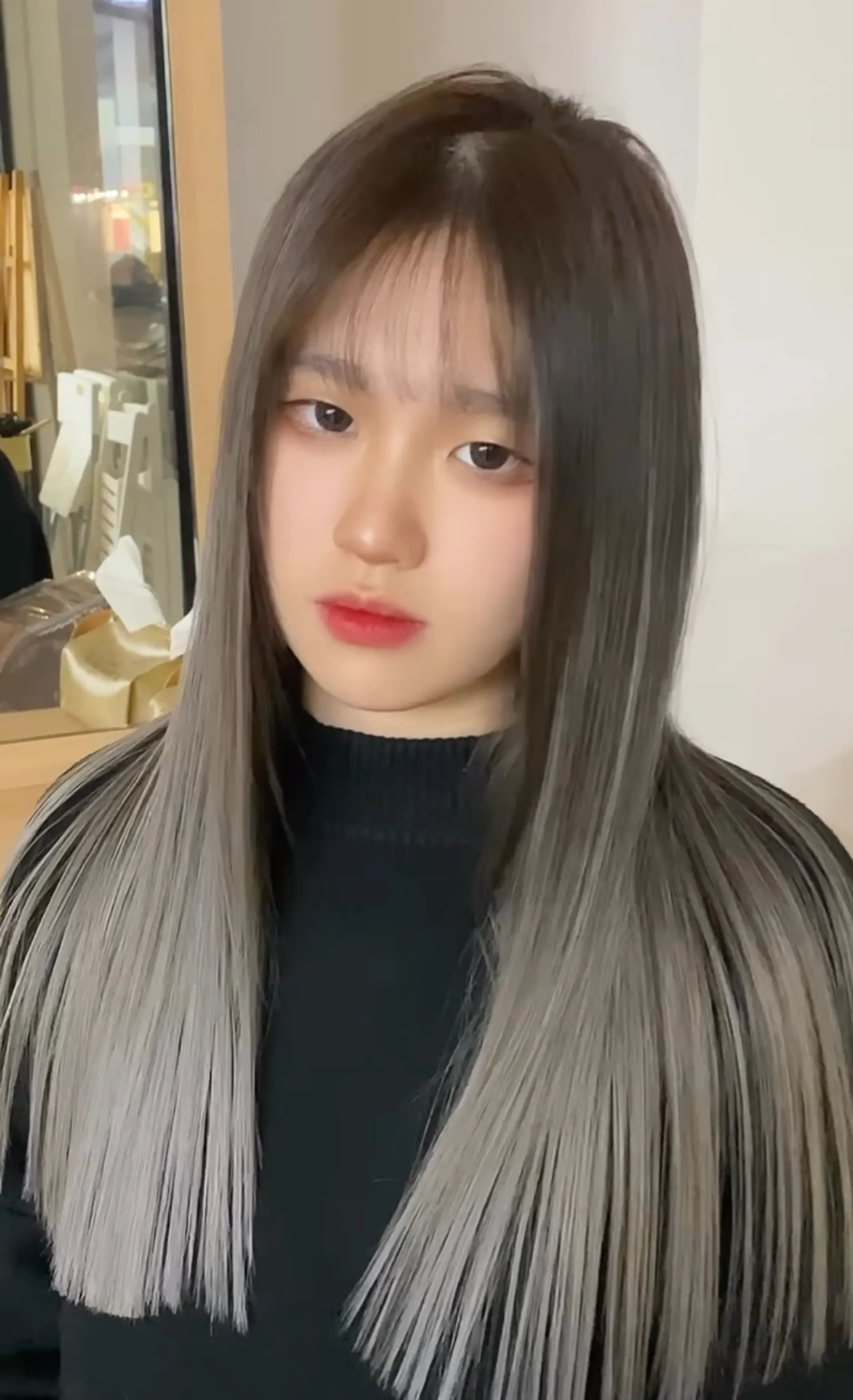 Long, straight hair with dark brown roots transitioning to silver at the ends, complemented by wispy bangs. 1