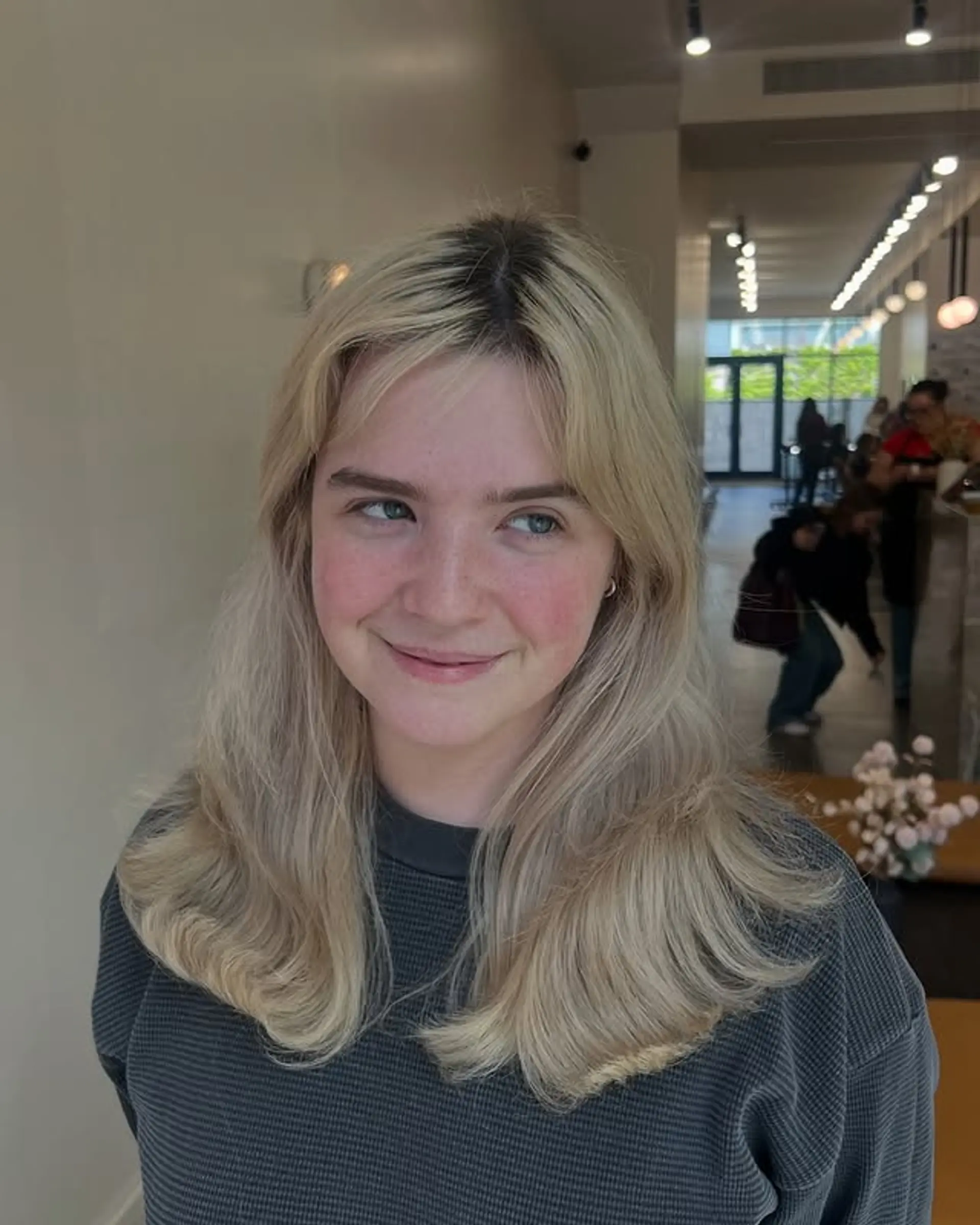 A wavy medium-length hairstyle with face-framing curtain bangs and blonde balayage. 1