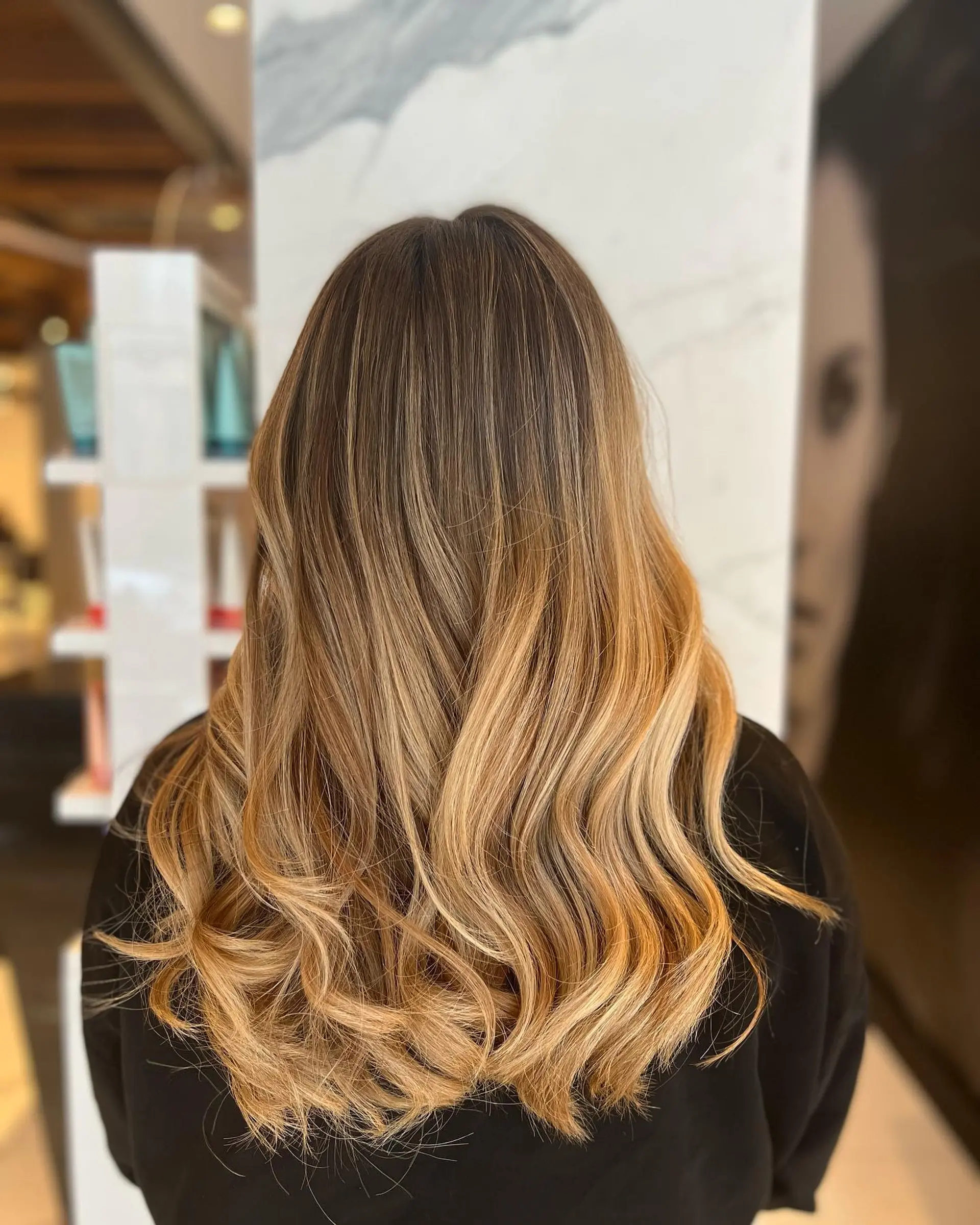 Long hair featuring a seamless golden honey blonde foilayage melt styled into loose, flowing waves. 1