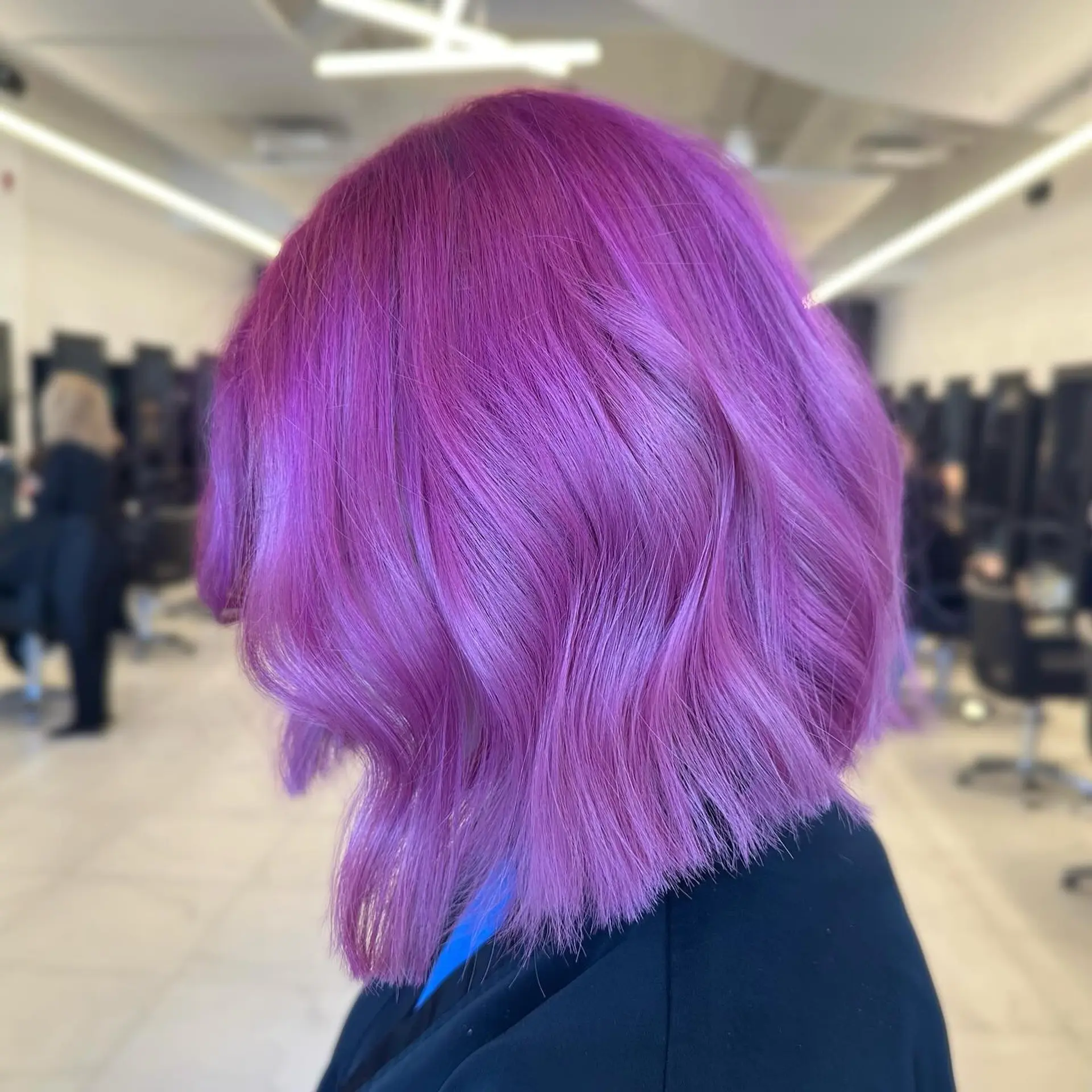 A bold, all-over vivid magenta-purple bob styled with soft waves and textured blunt ends. 1