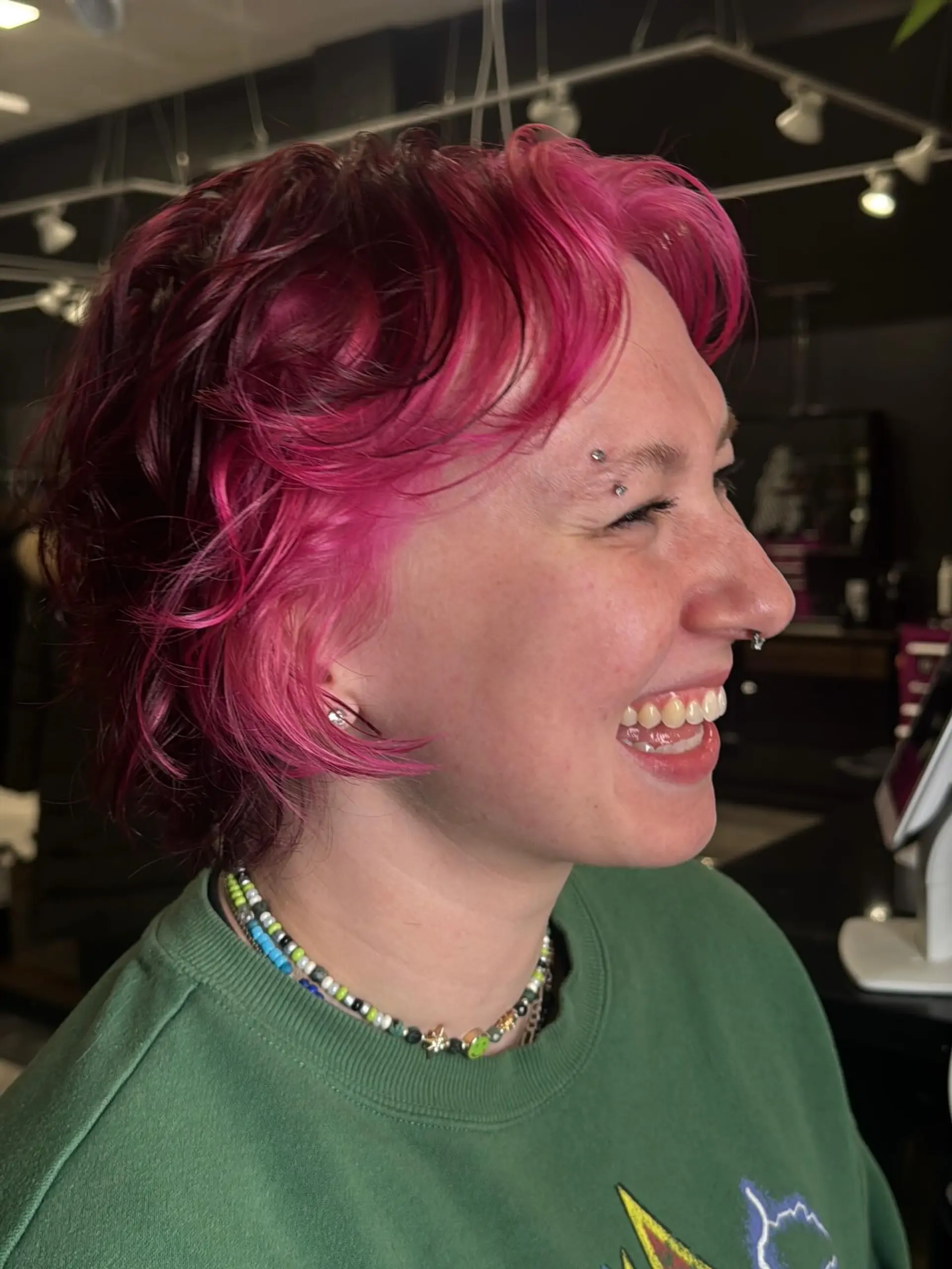 A short, edgy shag pixie cut with choppy layers and natural wavy texture, colored in a vibrant hot pink hue. 1