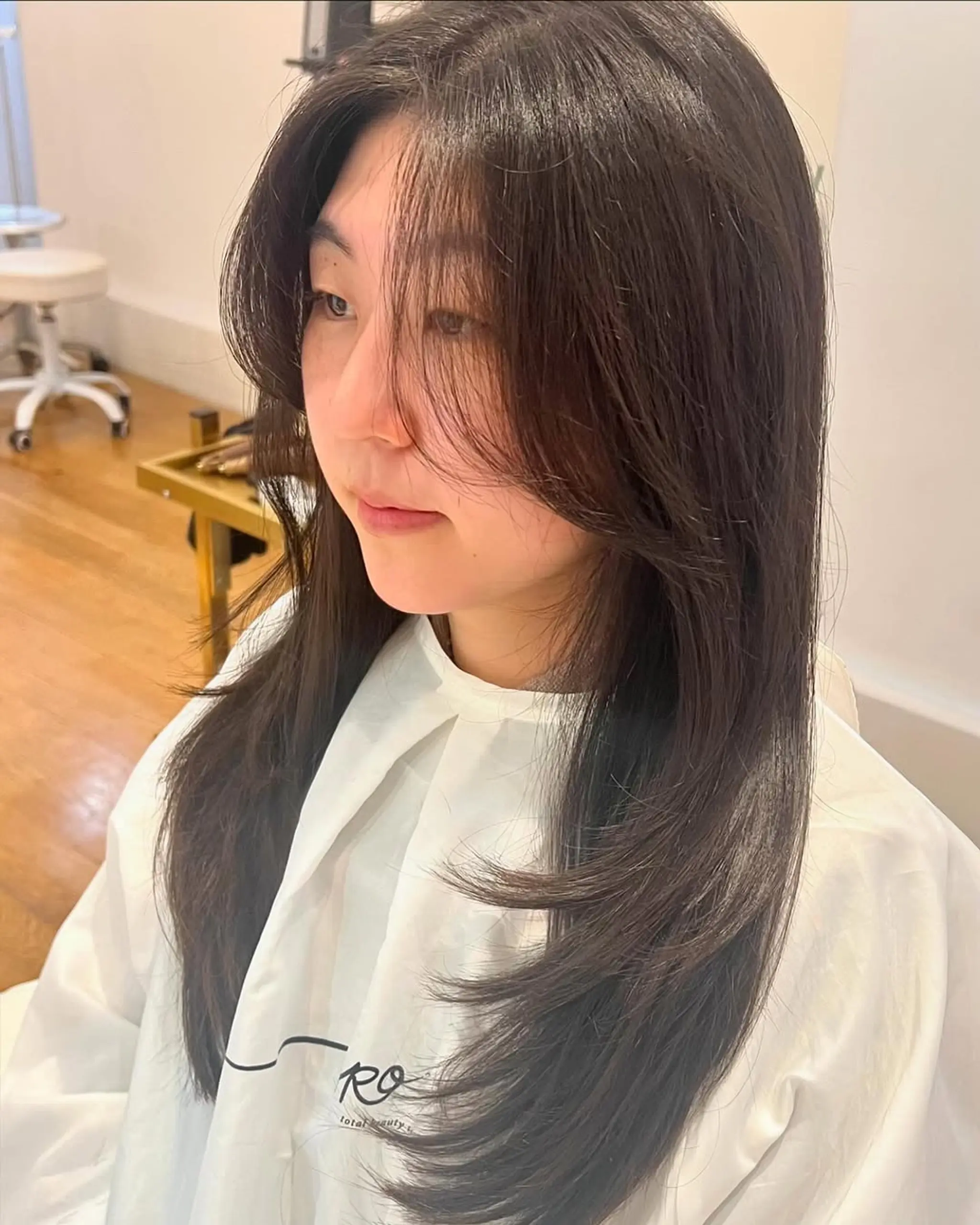 A long, straight hairstyle with face-framing layers and curtain bangs.