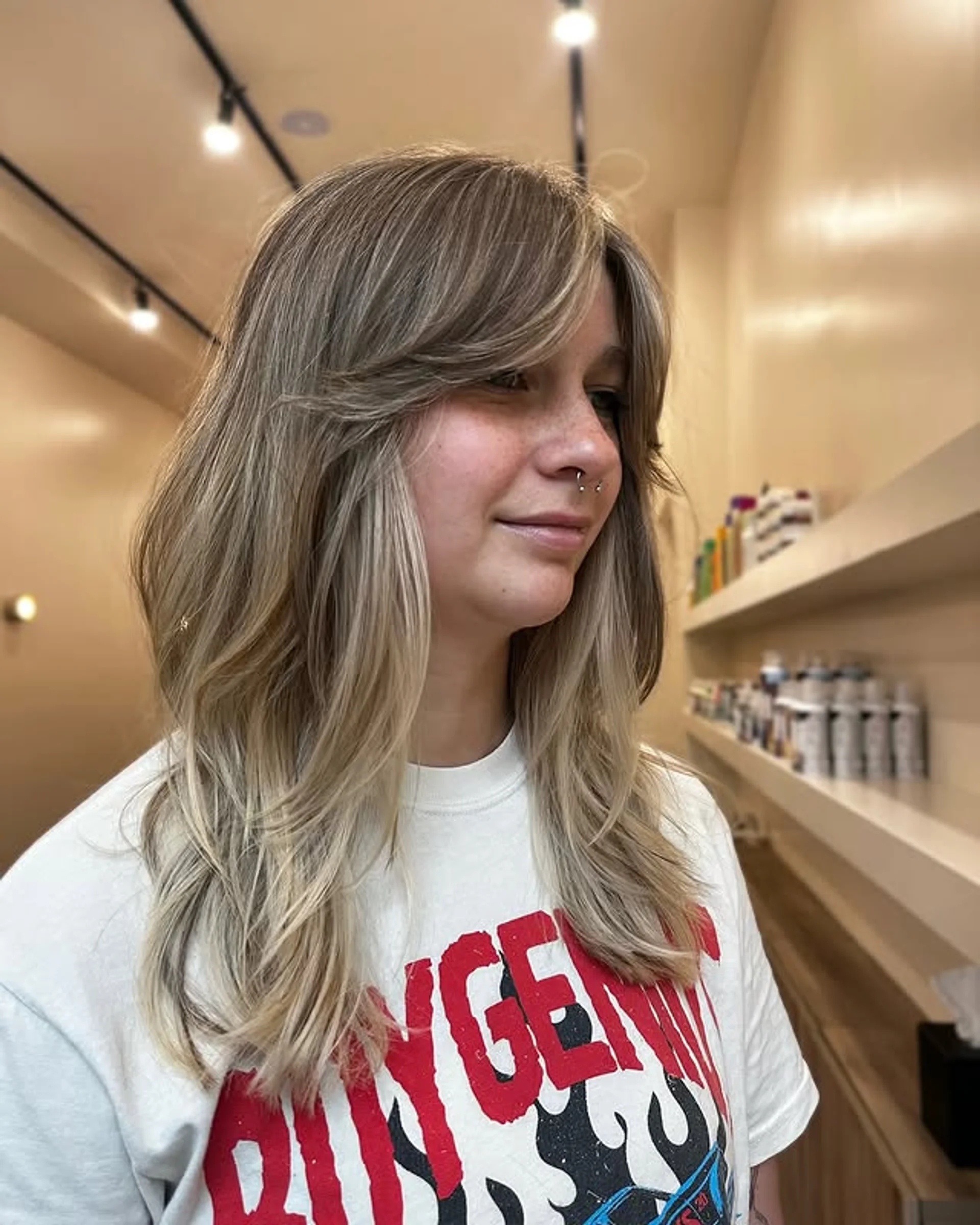 A medium-length layered haircut with curtain bangs, styled with a voluminous blowout. - Preview 2