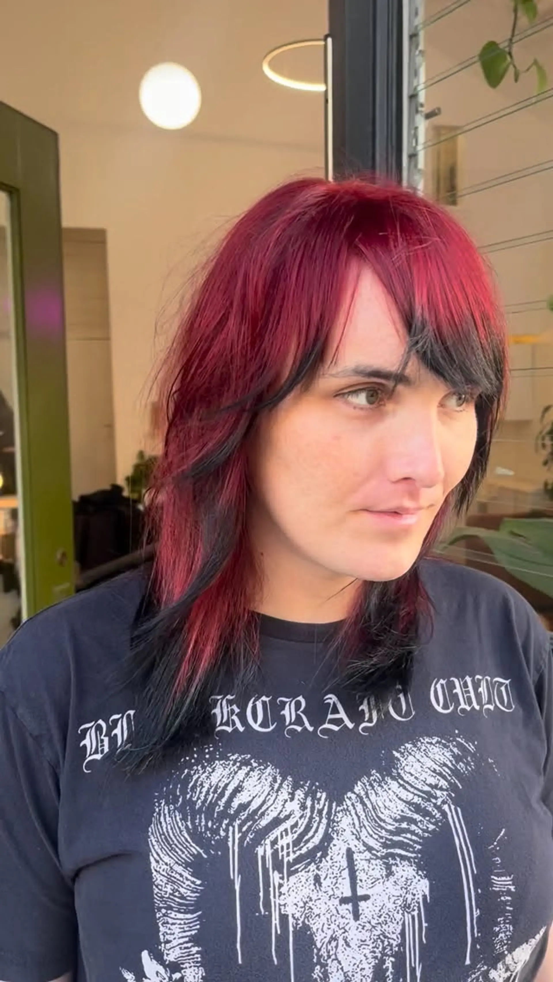 A layered two-tone scene shag featuring vibrant crimson red hair paired with black peekaboo lowlights and choppy textured bangs. 1