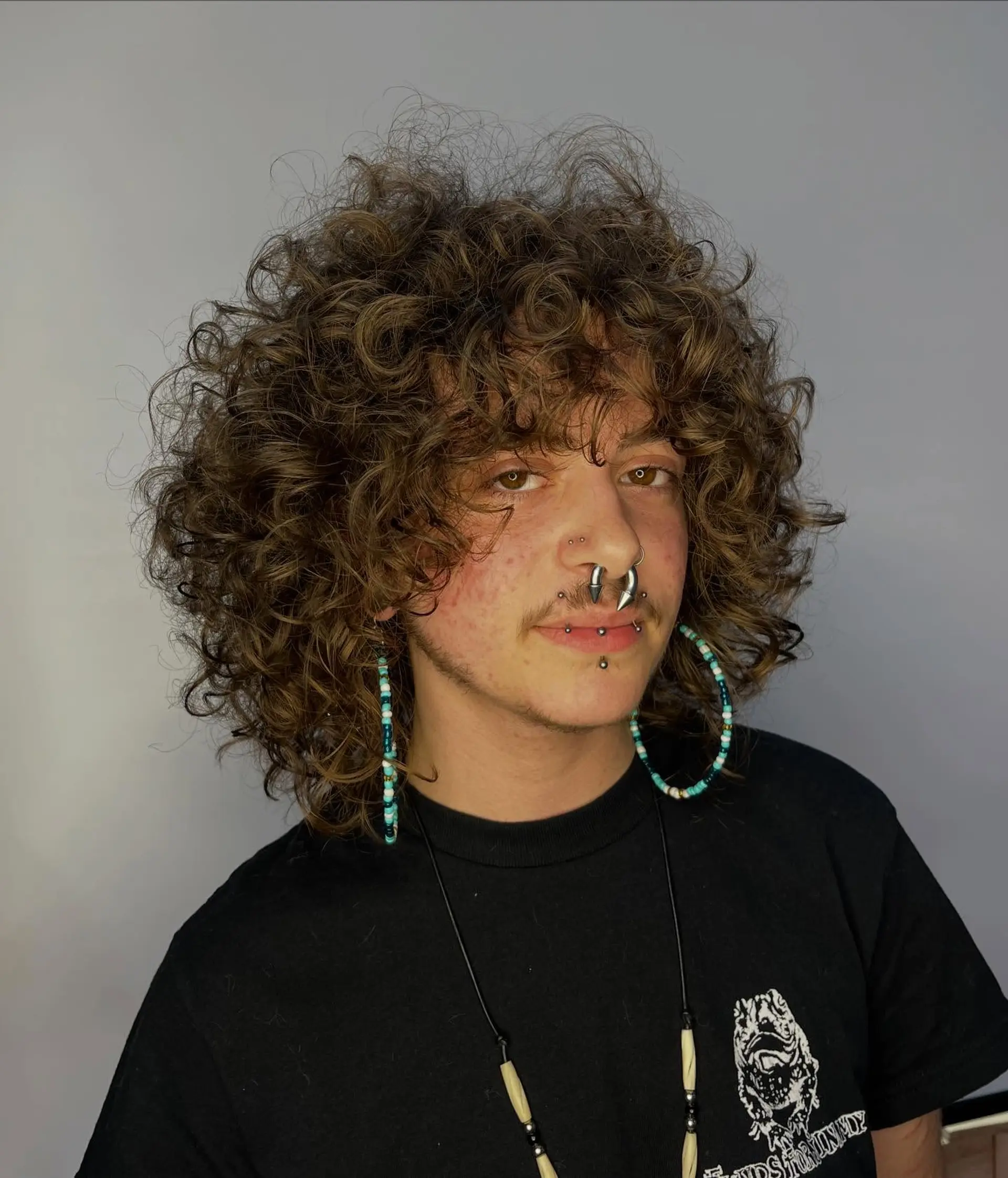 A textured medium-length curly shag featuring soft face-framing fringe and defined round layers. 1