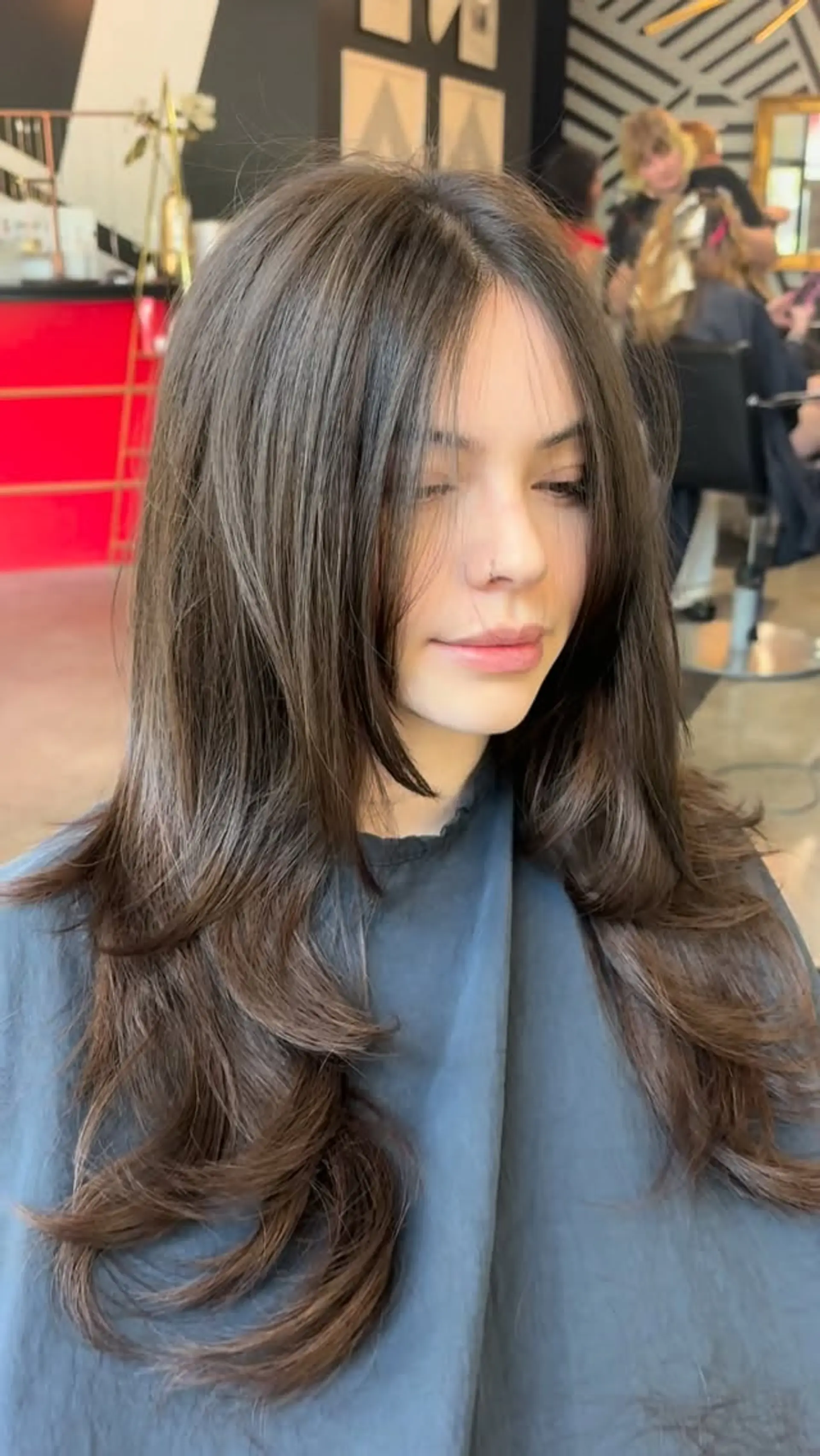 Long dark brown hair featuring soft, face-framing layers and a wispy parted fringe, finished with subtle textured flips at the ends. 1
