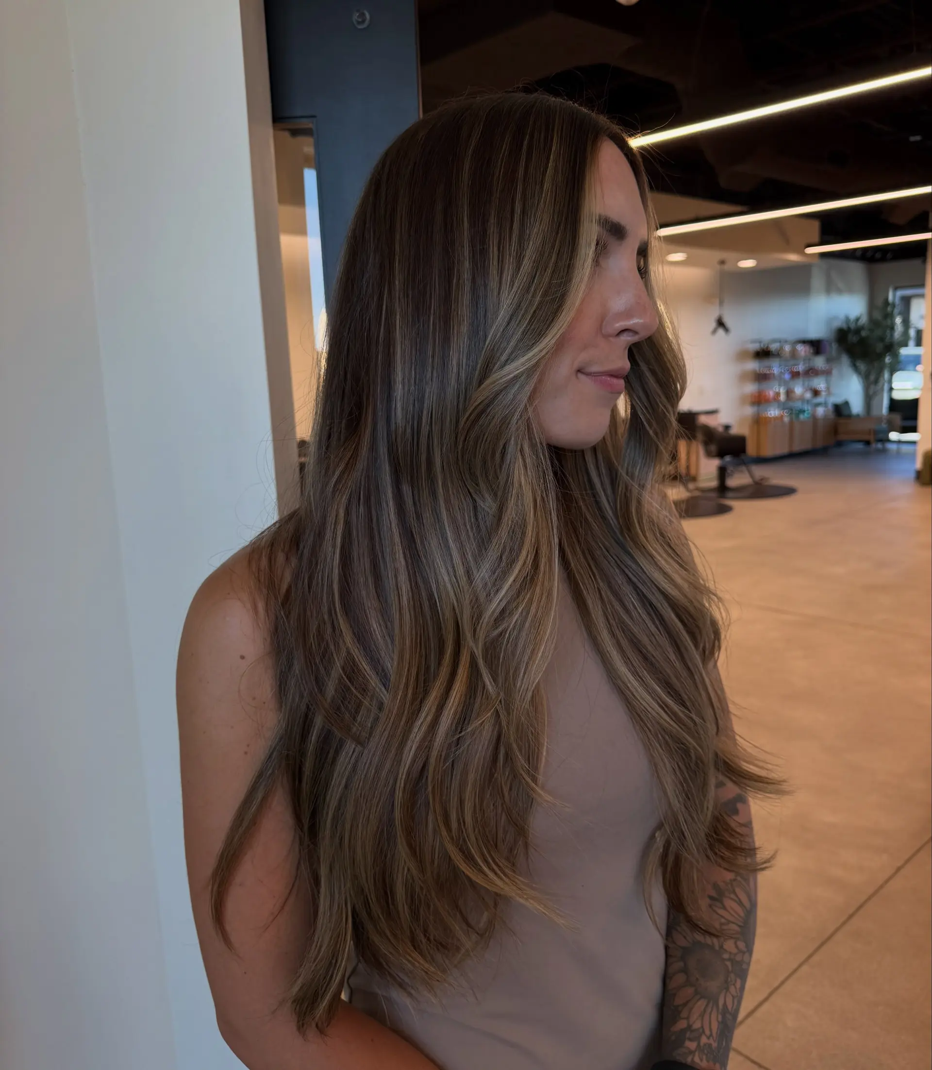 Long dimensional brunette hair styled into cascading soft waves with seamless balayage highlights. 1