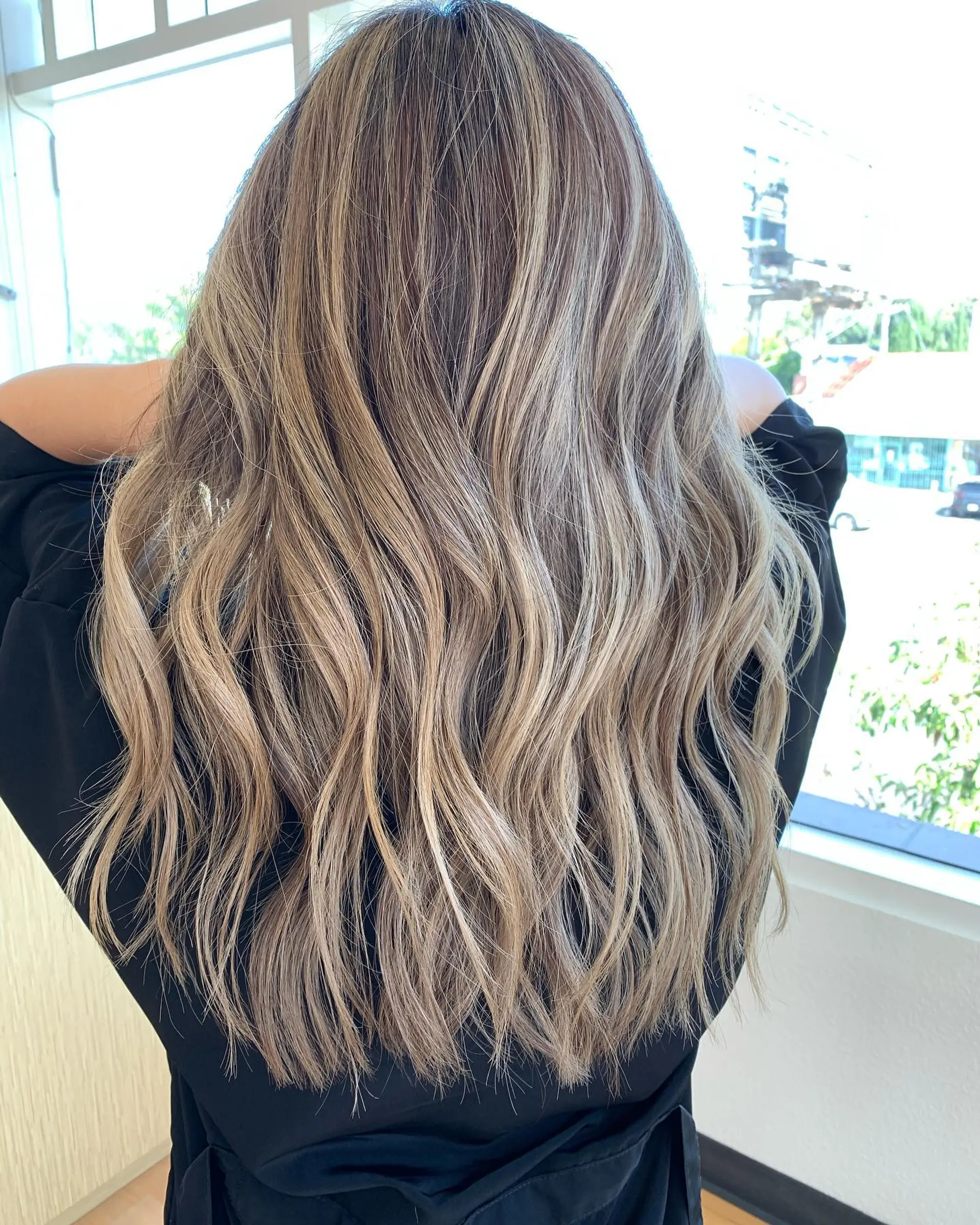 Long dimensional ash blonde highlights over a light brown base styled in loose, lived-in waves. 1