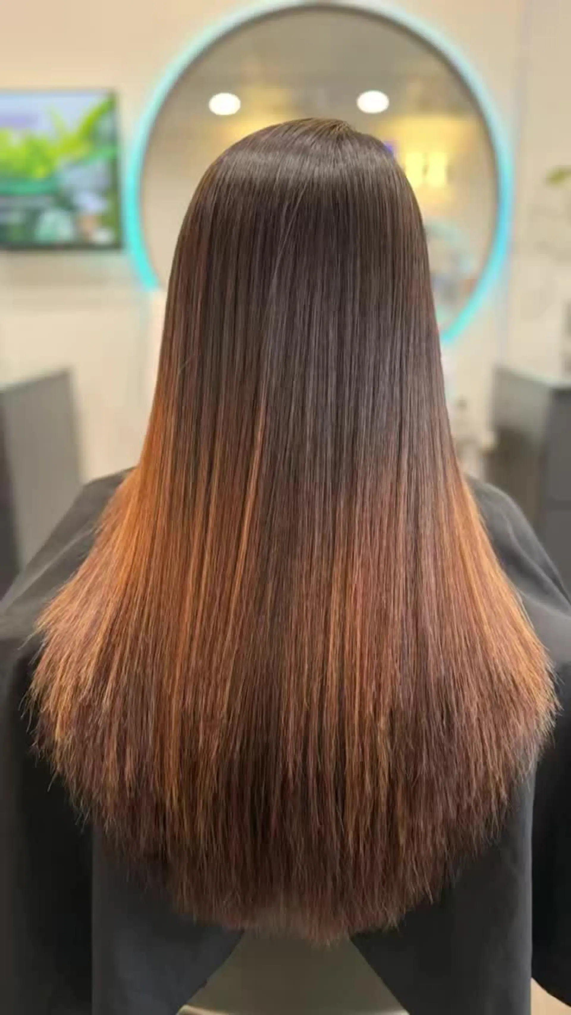 Long, silky straight brunette hair with warm caramel undertones toward the mid-lengths and ends, styled in a polished, pin-straight finish. 1