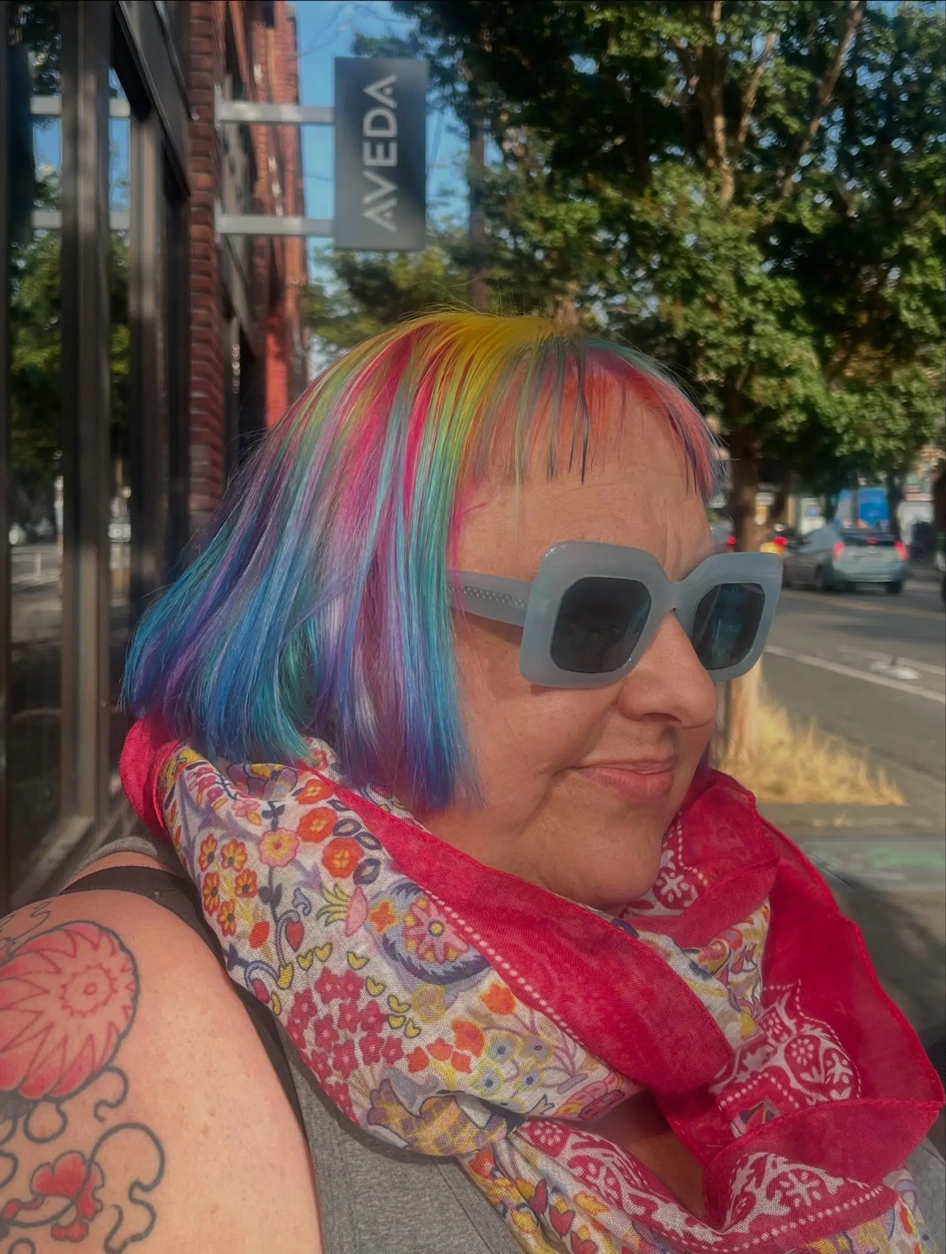 A sleek, chin-length bob with wispy micro bangs featuring an iridescent multi-color blend of yellow, pink, purple, and blue. 1