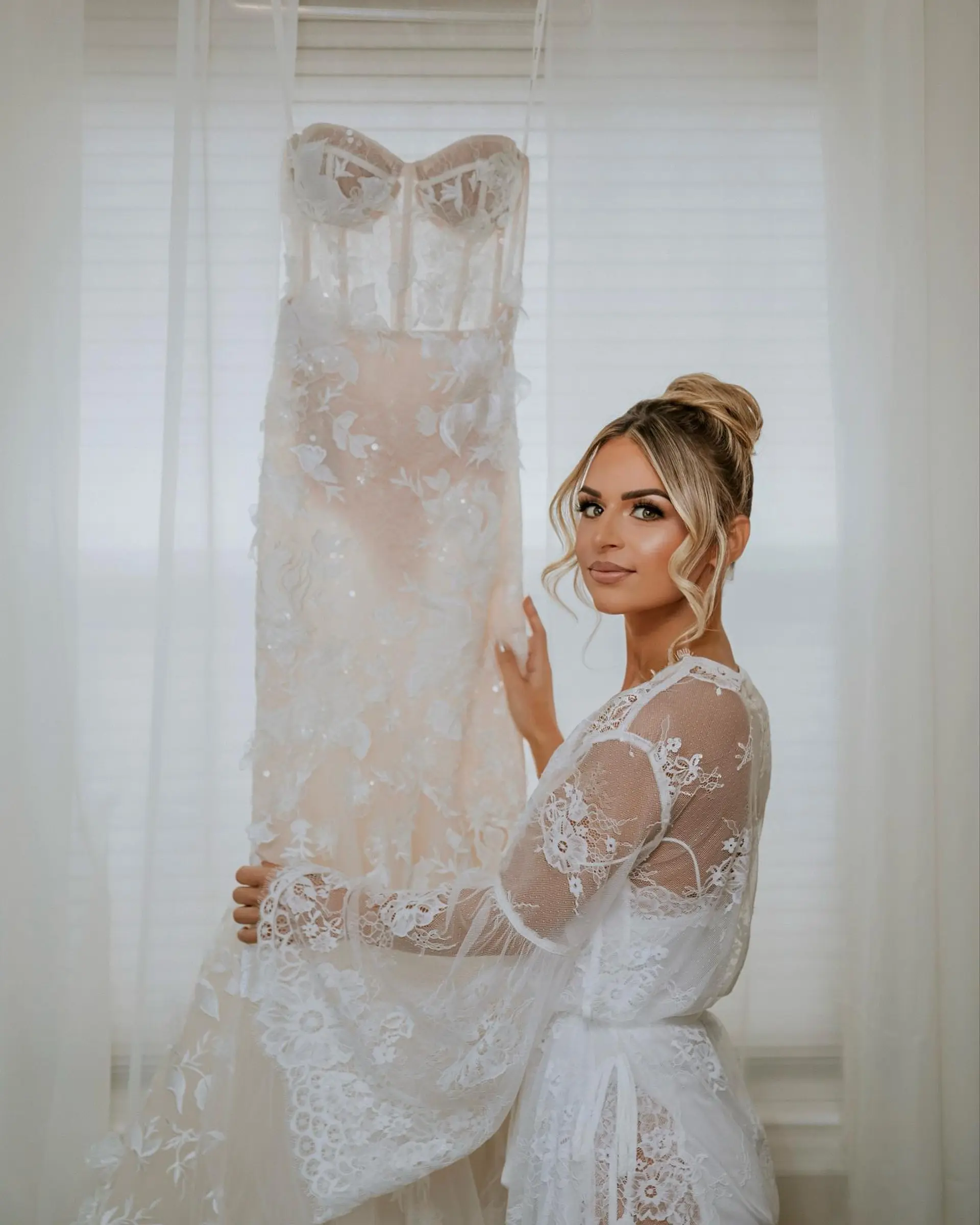 A sophisticated bridal high bun with soft, curled tendrils framing the face. 1
