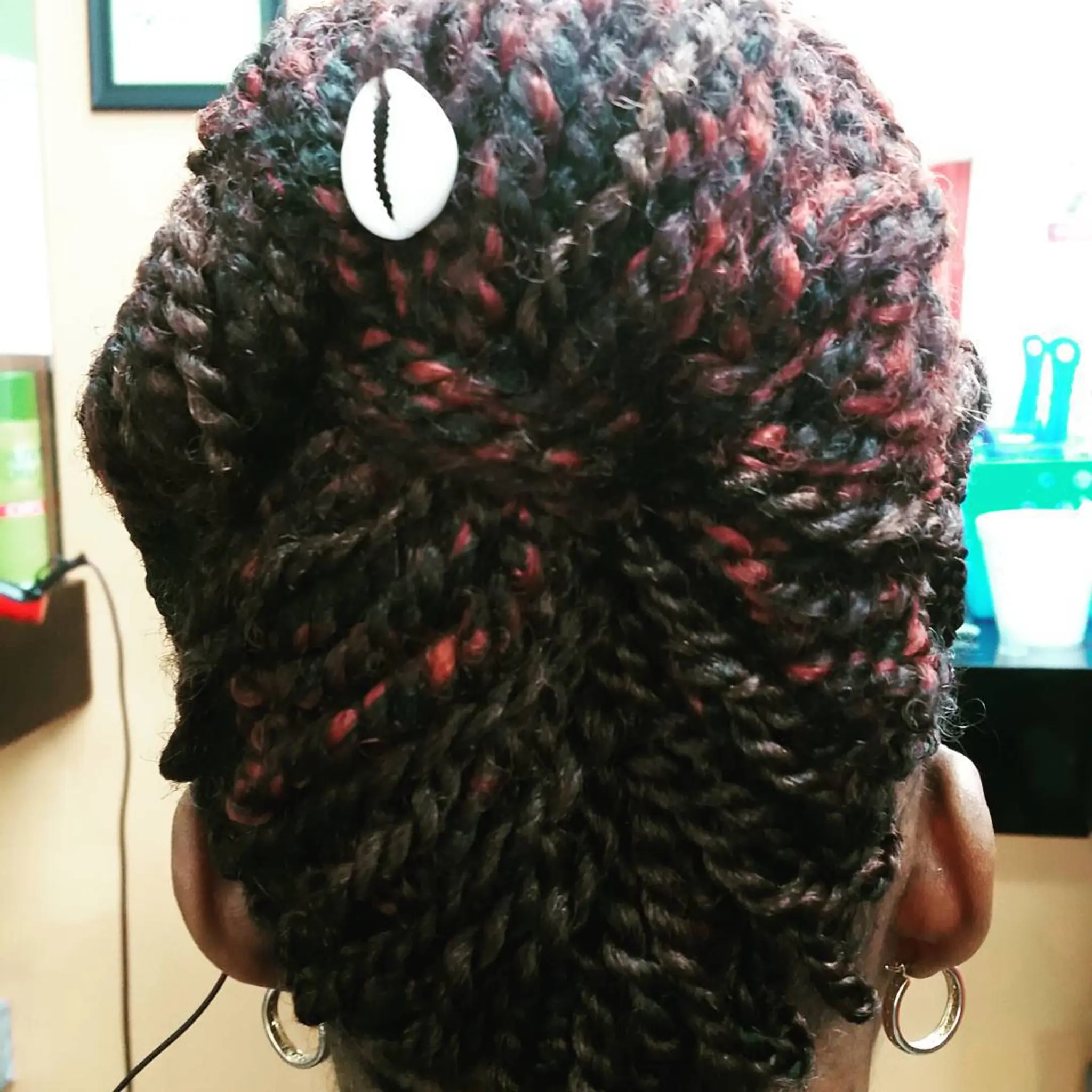 A medium-length twist out updo hairstyle with a cowrie shell accent.