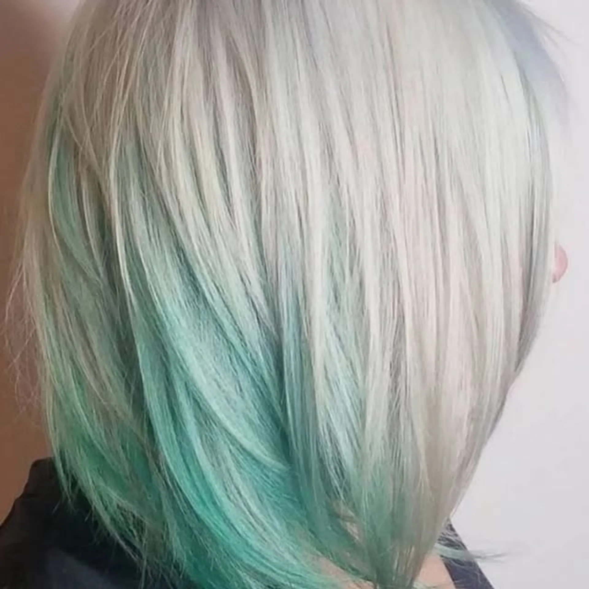 A model with a medium-length wavy teal razor shag haircut and fringe bangs, showcasing the 2026 hair color of the year, Transformative Teal. - Preview 1