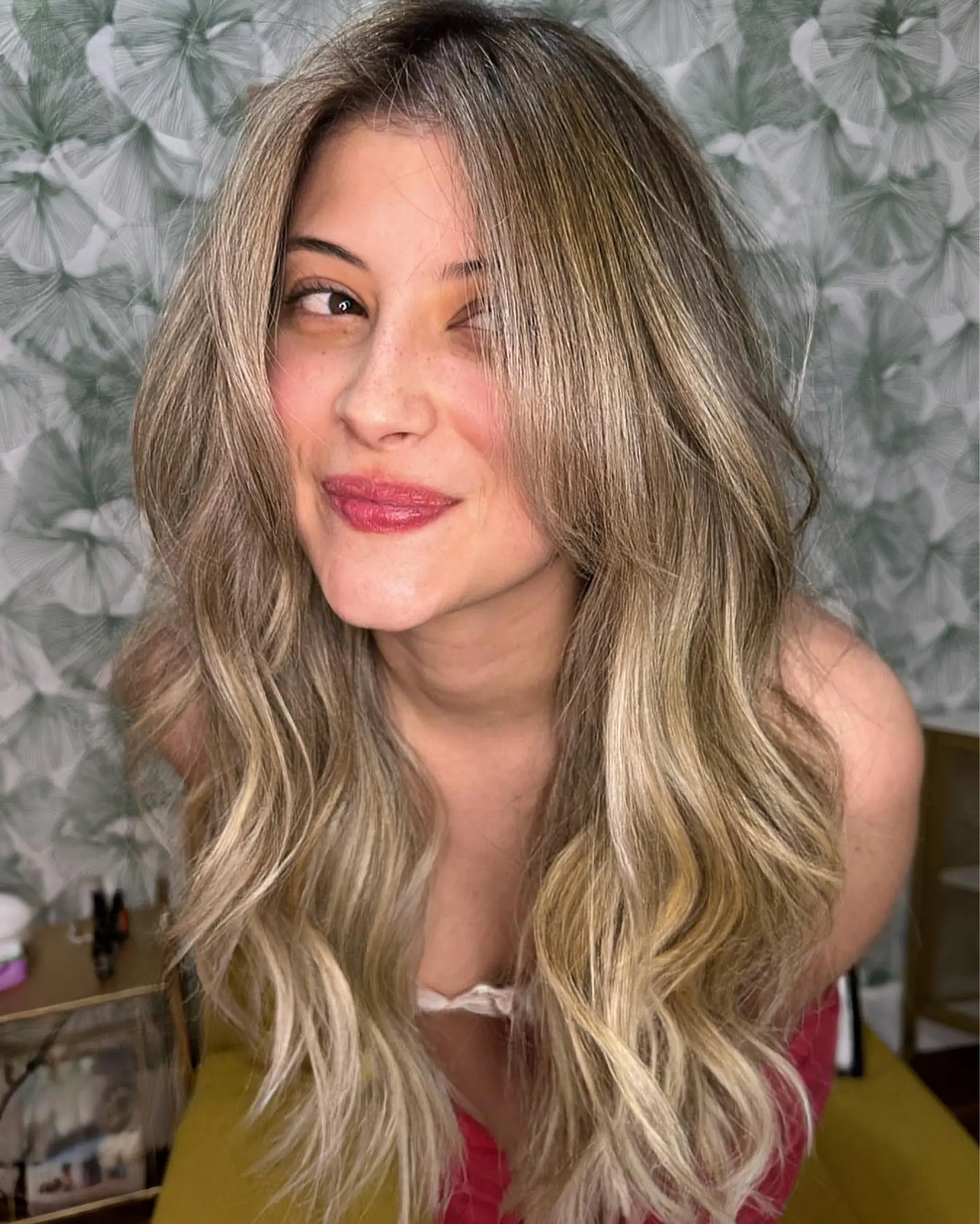 Long dimensional ash blonde hair styled in soft, bouncy waves with face-framing curtain layers. 1
