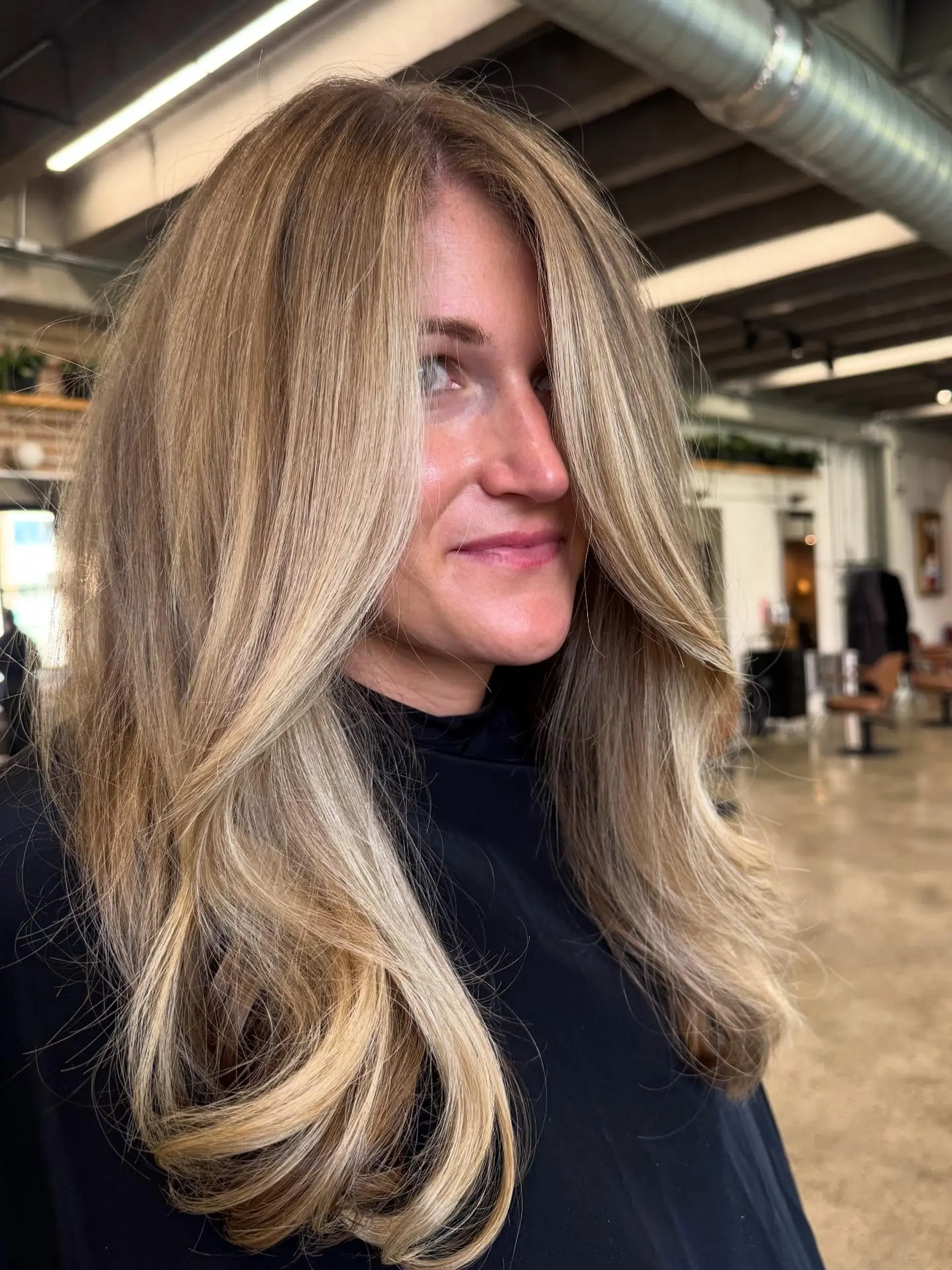 This long, wavy hairstyle showcases soft, flowing layers with a face-framing cut that adds volume and movement. The hair is styled with loose, bouncy curls, highlighting the natural-looking balayage effect. 3