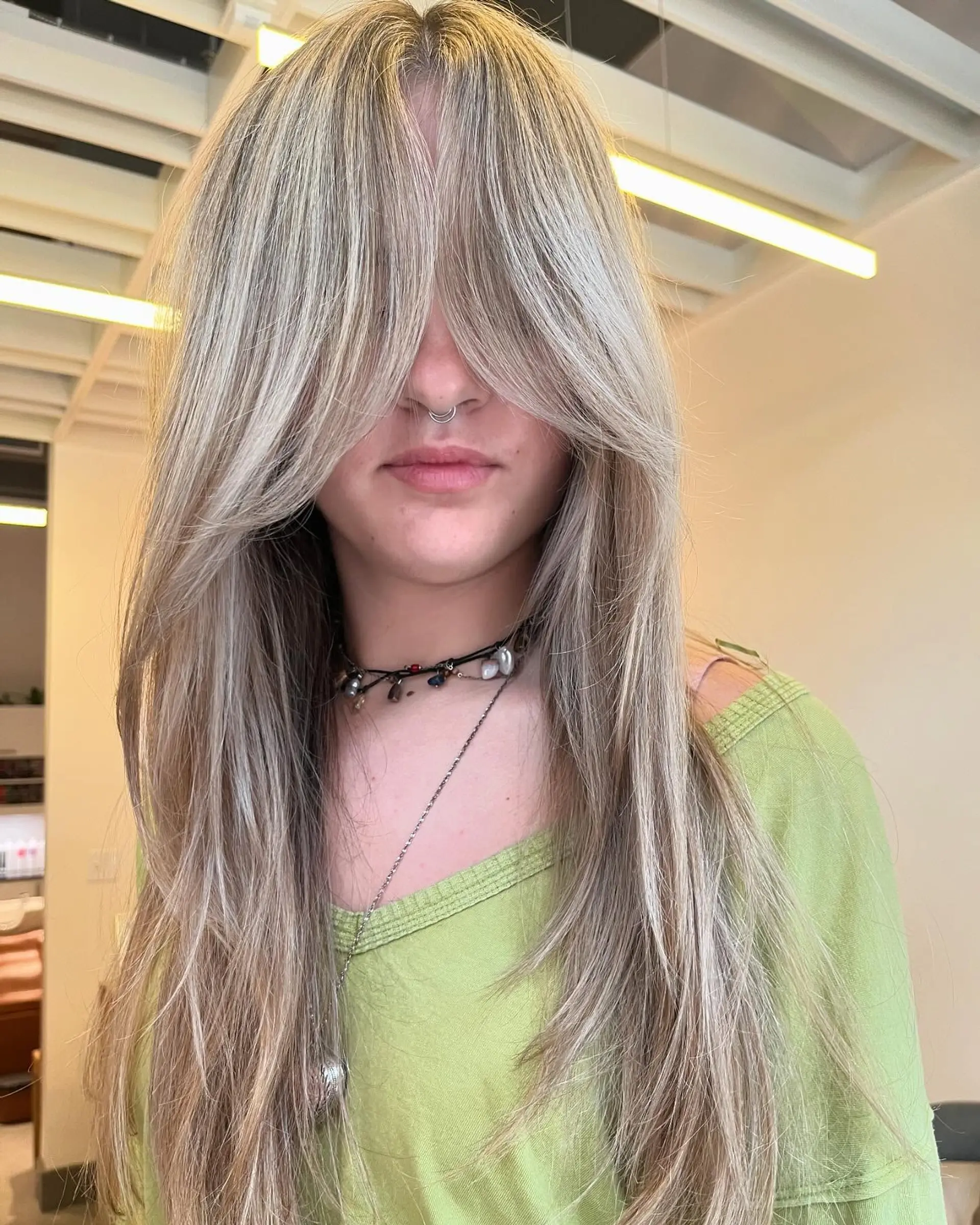 Long ash blonde hair featuring dramatic, face-framing curtain bangs and feathered layers. 1