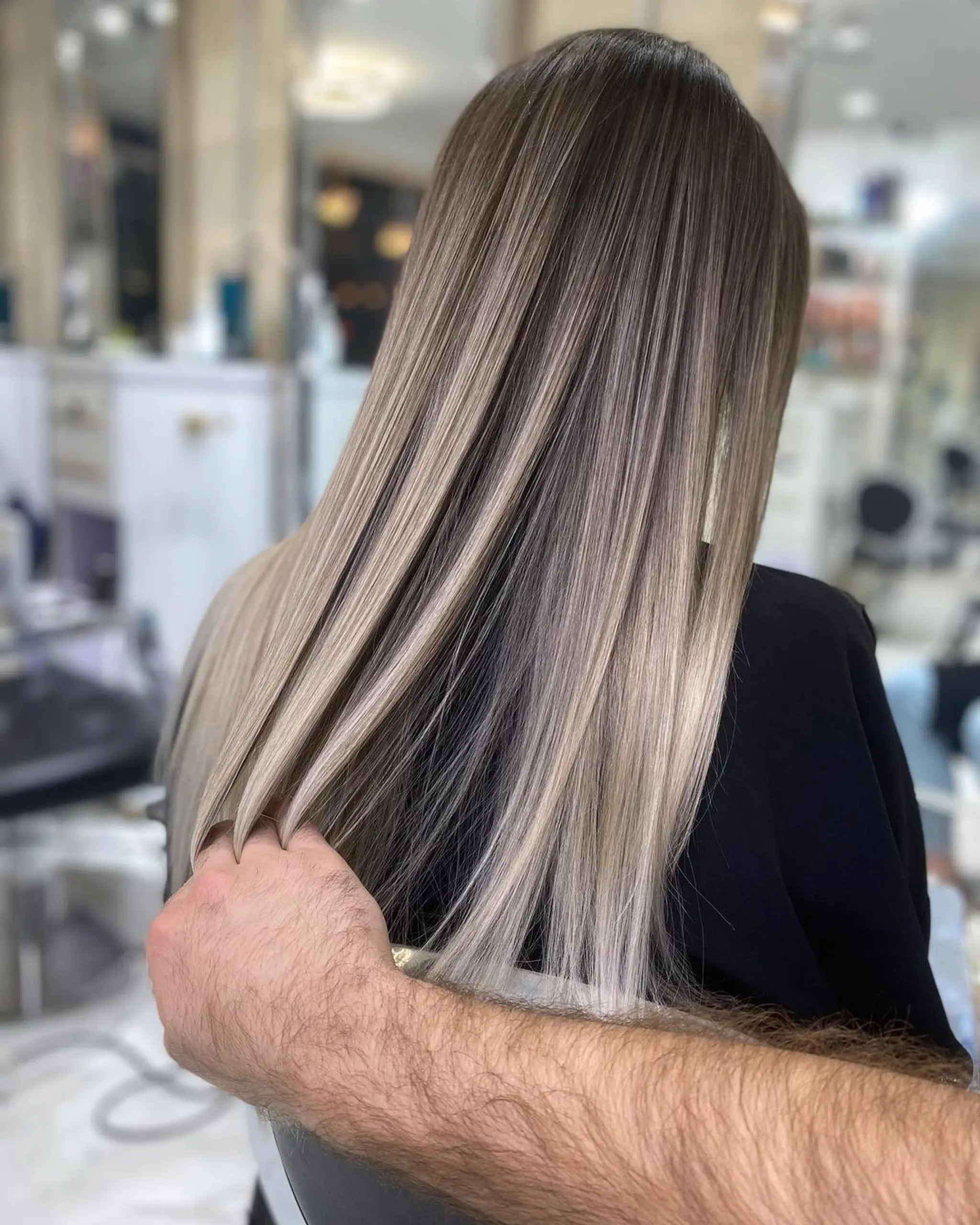 Seamless blend from ash blonde to platinum blonde in a sleek, straight, and very long style.