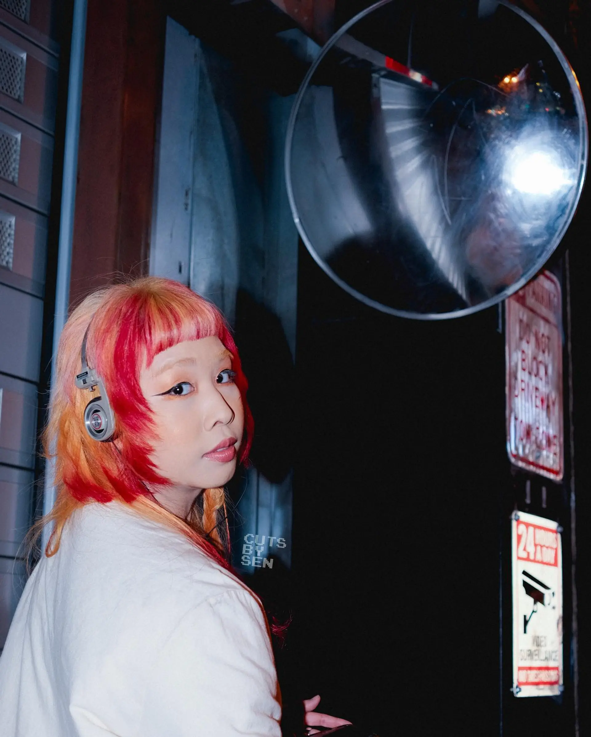 A modern, edgy variation of the hime cut featuring blunt micro bangs, sharp face-framing step layers, and vivid two-toned color blocking in red and warm peach. 1