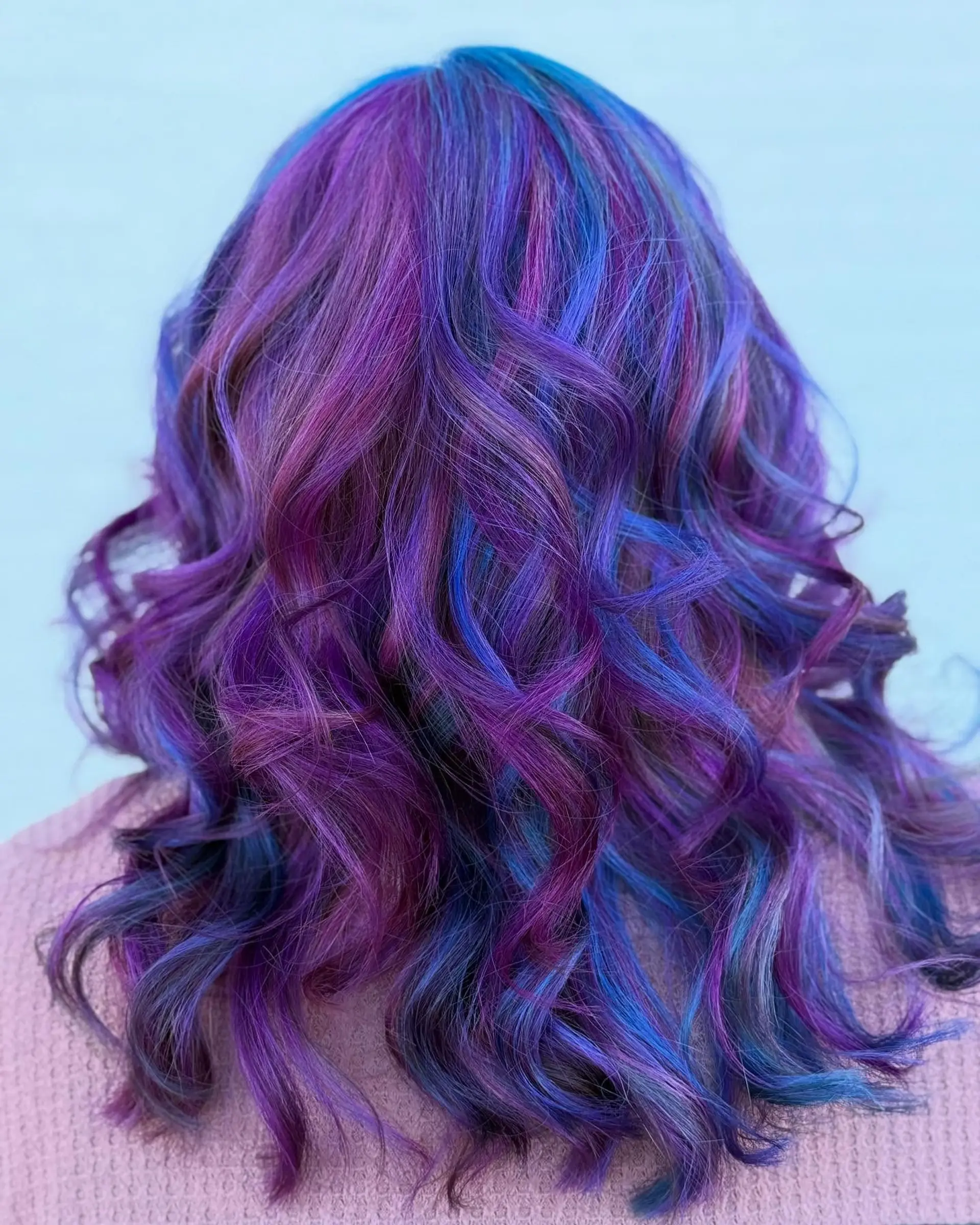 Medium-length hair featuring a dimensional blend of vivid purple, magenta, and sapphire blue tones styled in loose waves. 1