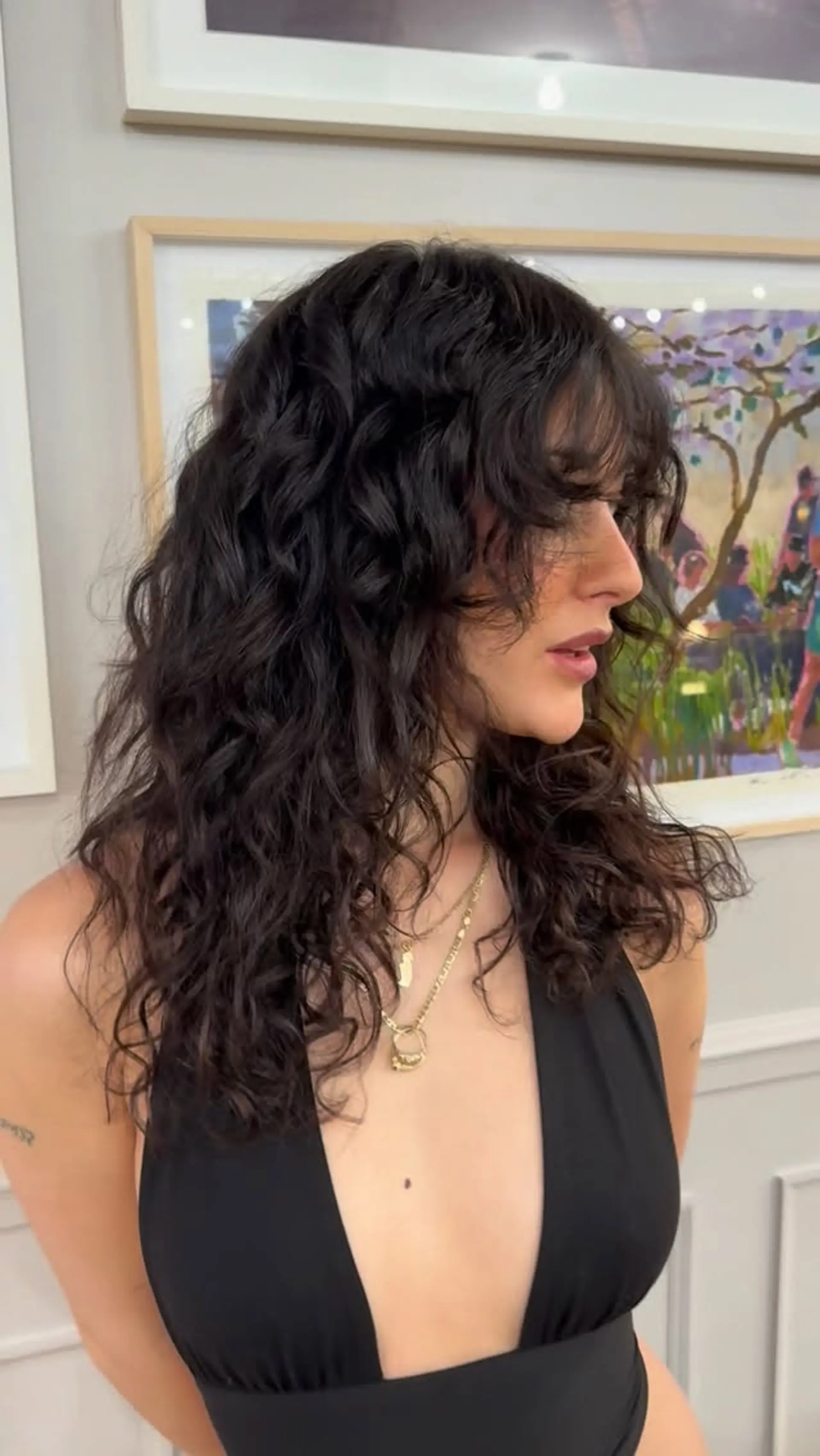 Medium-length dark curly hair styled into a voluminous shag cut with soft fringe framing the forehead. 1