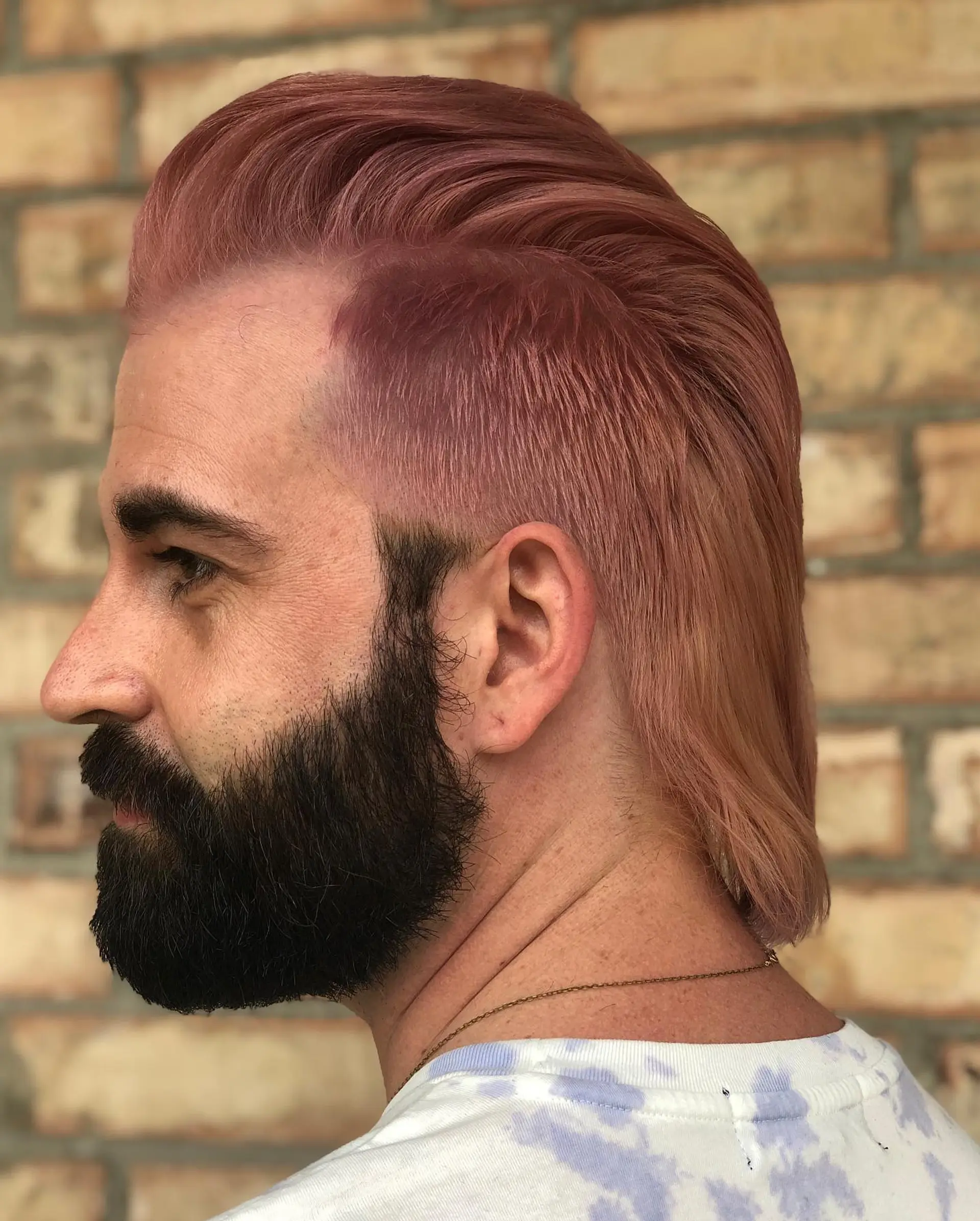 A modern mullet styled with swept-back volume on top and length flowing down the nape, colored in a uniform soft pastel pink tone. 1