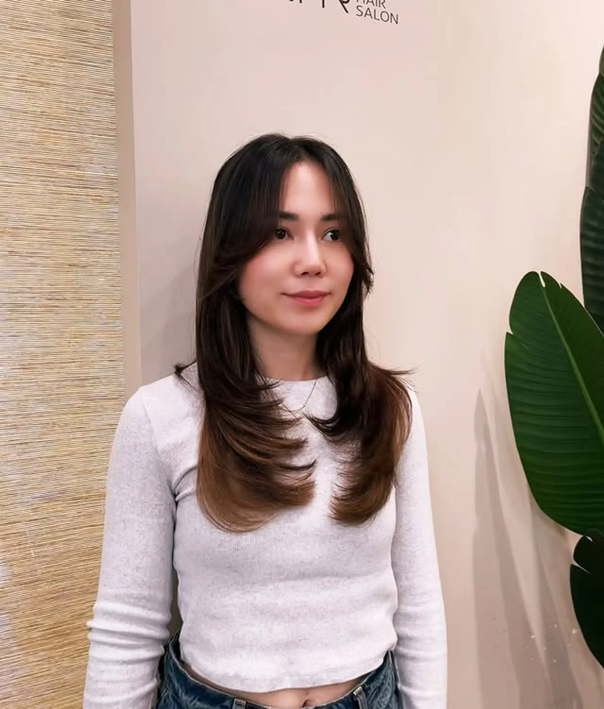 A layered haircut with face-framing layers and curtain bangs, styled with a subtle ombre color. 1